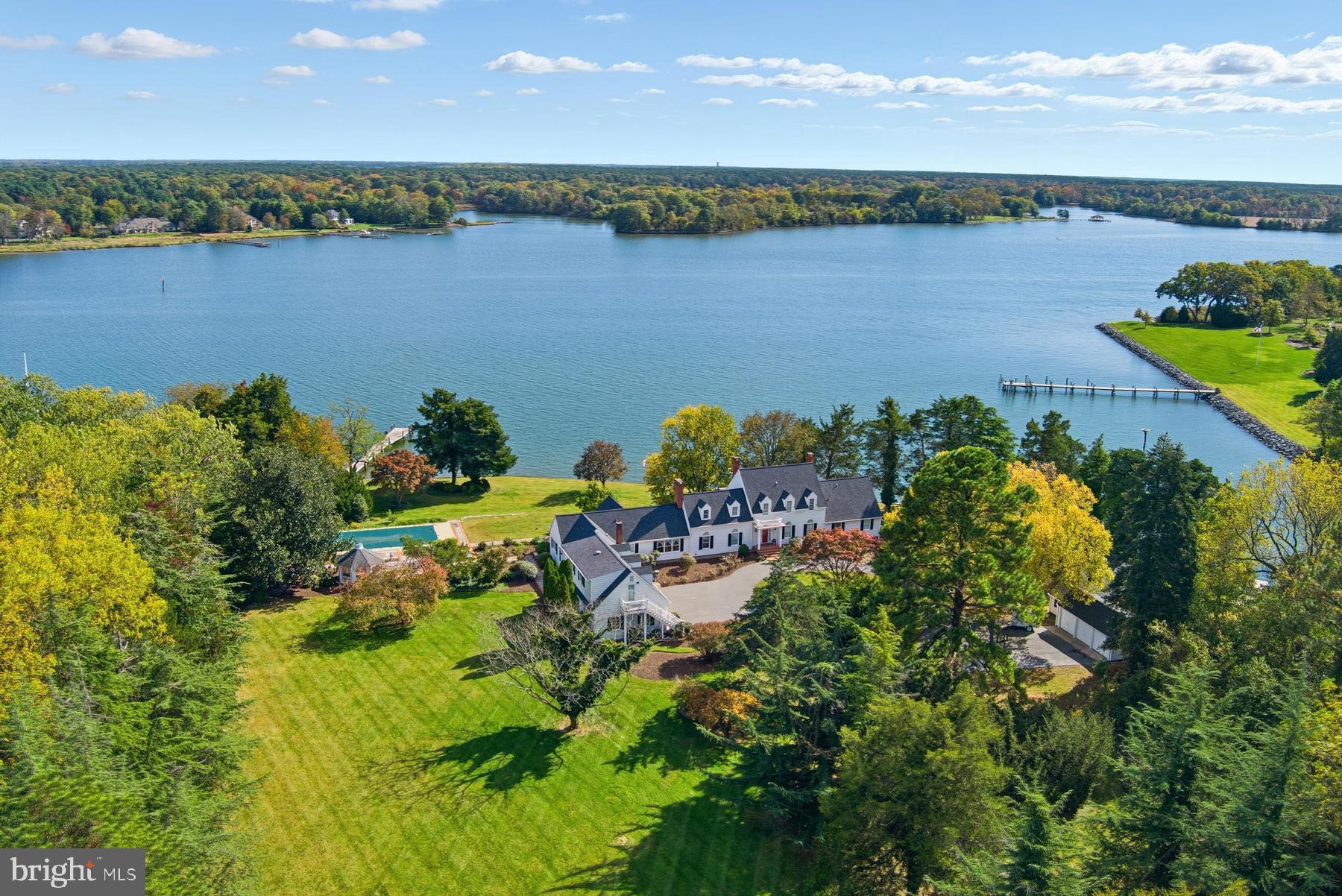 Beautifully sited on 17.7 acres along the Miles River in one of Easton’s most coveted locations, this quintessential coastal property embodies the essence of Eastern Shore living - casual elegance, timeless architecture, and a seamless connection to the water from nearly every vantage point. The 4,665 sq. ft. residence offers 4–5 bedrooms and 5.5 baths, with formal dining and living rooms, and a cozy den opening to a waterside sunroom and patio. The large kitchen, complete with center island, custom built-ins, and dining area, flows into a bright family room that leads to a covered porch overlooking the river. A butler’s kitchen, laundry area, and adjacent full and half baths add convenience, while a breezeway connects to the attached three-car garage with a guest apartment above. Outdoor living shines with a private dock (two slips, 3.5' MLW), 585 feet of bulkheaded shoreline, a large gunite pool with adjacent gazebo, mature landscaping, and extensive hardscaping. Additional improvements include a detached three-bay garage and a waterside shed for storage and equipment. Owned by the same family since 1978, this exceptional property presents a rare opportunity for a new buyer to personalize a legacy waterfront estate. Note: Approximately 15 acres are enrolled in a Forest Stewardship Plan. Applications have been submitted to Talbot County for a new 4-bedroom septic system and reconstructed pier.