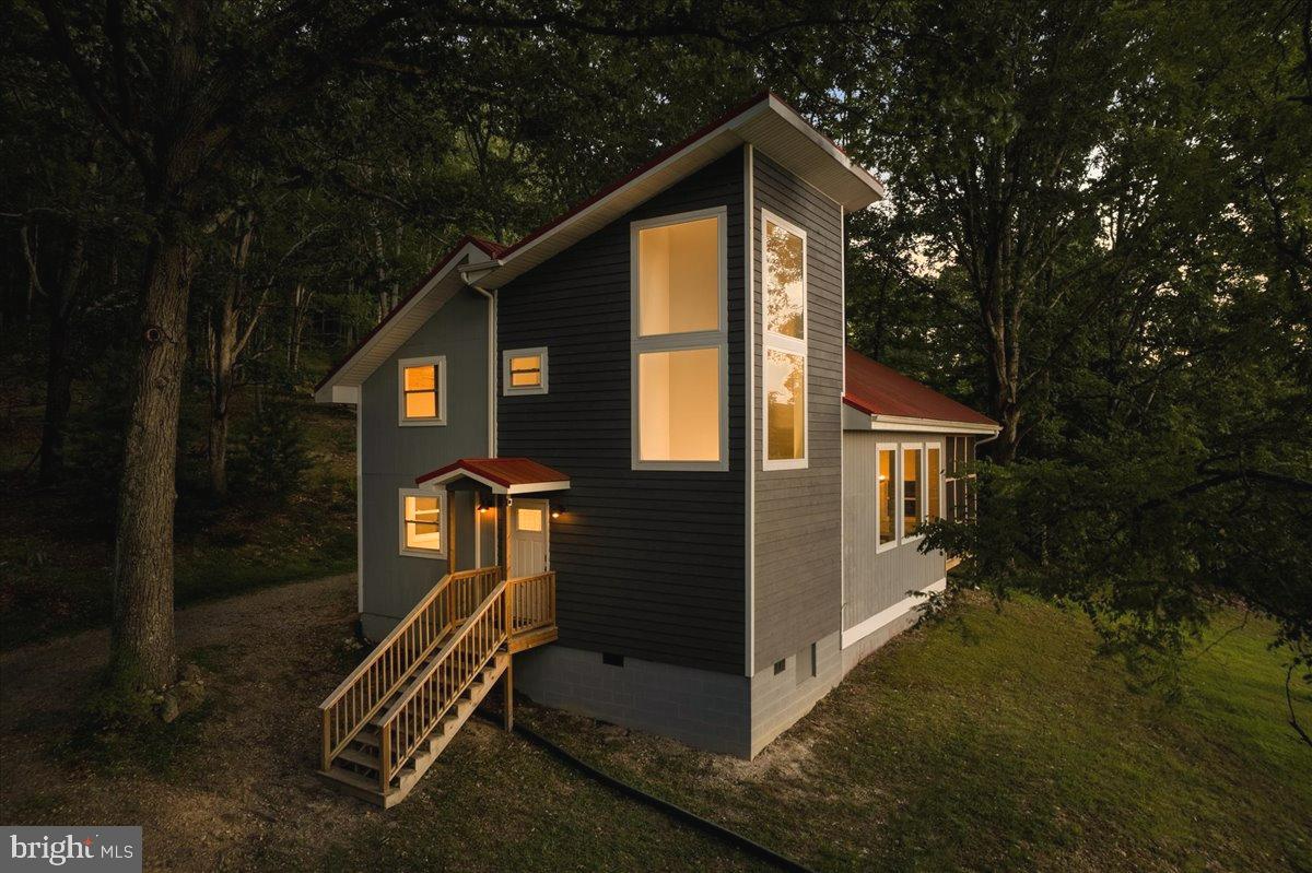 Full time residence, weekend getaway, or fully furnished and turnkey Airbnb, this property is stunning! Breath easily on 5 private wooded acres with breathtaking mountain views and exceptional privacy.  With 4 BRs and 2.5 baths, a deck and a screened in porch, there are multiple spaces for privacy or entertaining.  

Be sure to acquaint yourself with the very sought-after and unique Lost River, WV, with an easy , gorgeous drive from Northern VA!   This area offers the perfect blend of mountain serenity, outdoor adventure, and small-town charm. Lost River is loved for its peaceful setting, wooded ridge lines, star-filled skies, and easy access to some of West Virginia’s most beautiful natural amenities.

Just minutes away, Lost River State Park offers miles of hiking and biking trails, horseback riding, seasonal swimming, cabin getaways, picnic areas, and the breathtaking Cranny Crow overlook with expansive mountain views. The surrounding area is also known for its local art, farm markets, charming shops, casual dining, and nearby must see destinations such as Wardensville, Lost City, and the greater Potomac Highlands region.

Whether you are seeking a full-time residence, weekend retreat, or investment property, Lost River offers an inviting escape from the pace of everyday life—where mornings feel quieter, nature is always close, and the lifestyle is centered around relaxation, recreation, and connection to the mountains.

This home offers bundant windows throughout fill the home with natural light, highlighting the spacious open-concept design. The living room features soaring vaulted ceilings and a beautiful stone fireplace, creating a warm and inviting atmosphere.

The contemporary kitchen is thoughtfully crafted for both daily living and effortless entertaining, featuring stainless steel appliances, elegant quartz countertops, and a spacious center island with ample seating
Unwind in the serene primary suite, complete with a spa-inspired bathroom featuring a separate soaking tub, walk-in shower, and luxurious finishes.
Move-in ready and income-producing, this exceptional property combines luxury, comfort, and natural beauty in an unforgettable mountain setting.