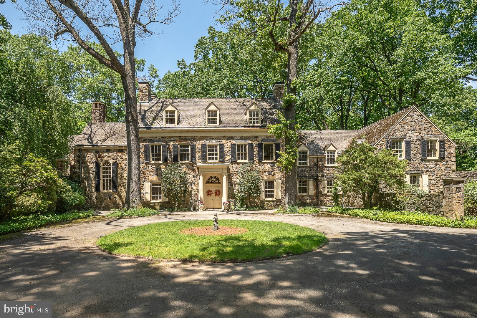 Wayne, 19087. Rare offering. A highset 6+acre 1920's estate compound with the ultimate luxury of total privacy. Georgian Colonial manor house and estate sanctuary has wild, forested woodlands, formal, sunken gardens, tennis court, and pool w pool house, none of which can be seen from the street. The long drive leads to a delightful, walled court yard with circular drive at front approach to the manor house, a grand Pennsylvania fieldstone colonial of approximately 9,000 square feet. The manor house has endless 1920's scale, elegance and amenities, including the barrel-vaulted transverse entrance hall, formal step-down reception rooms with soaring ceilings and fireplaces,  quarter sawn hardwood floors, a graceful spiral stair rotunda, hand-paneled library, breakfast room and dressing room of tiger maple, a hidden cloak room and service bar for entertaining and spacious outdoor covered and open patio spaces, all with incredible views. This family compound includes a detached, four car heated garage with a chauffeur's two bedroom apartment above with full bath, laundry and kitchen.  Swimming pool and poolhouse has dual changing rooms, bathrooms and a kitchenette.