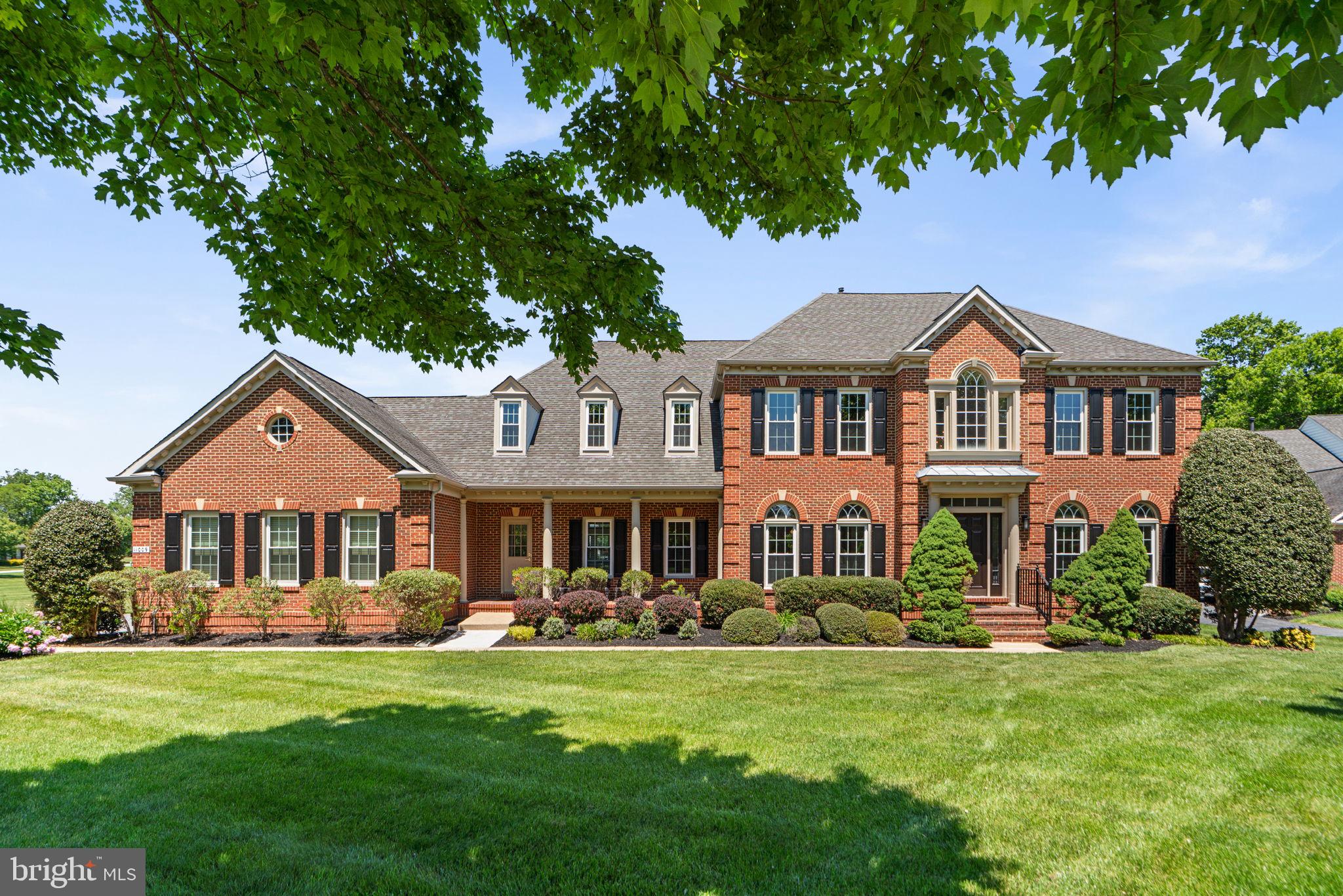 Offering an impressive 6,178 finished square feet, this beautifully updated residence combines timeless elegance with modern functionality through an extensive list of thoughtful interior improvements. Recent updates include updated windows, updated flooring across the main level and second floor, a recently installed garage door and rails, newly added quartz countertops (in the kitchen, primary bathroom, and garage), updated lighting throughout the first and second floors, refreshed door hardware, replaced water heater and water pump, and fresh paint throughout the home. // Sophisticated architectural details, including crown molding, wainscoting, elegant columns, arched windows, and a warm neutral color palette, create an inviting yet refined atmosphere, while open and airy living spaces add to the home’s luxurious appeal. Rich hardwood flooring flows throughout the dramatic two-story foyer and continues into the formal living room, accented with chair railing, and the elegant formal dining room featuring a modern chandelier and bright lower wall paint detail. The spacious family room is beautifully framed by columns and anchored by a stone-accented gas fireplace. Oversized windows flood the space with natural light, while dual sparkling chandeliers add a touch of grandeur. // The expansive eat-in kitchen is both stylish and functional, showcasing updated cabinetry, newly added quartz countertops, updated stainless steel appliances, a large center island with breakfast bar seating, a chic white subway tile backsplash, and elegant pendant lighting. The adjoining sunlit breakfast room features its own cozy gas fireplace and direct access to the screened porch, creating the perfect setting for indoor-outdoor living and entertaining. // Just off the kitchen, the well-appointed mudroom offers additional storage alongside a powder room and laundry room finished with luxury vinyl tile flooring. Also on the main level is a versatile bedroom with French door access, a walk-in closet, and an attached full bathroom—ideal for multigenerational living, guest accommodations, or a private home office or study. // Upstairs, four spacious bedrooms with luxury vinyl tile flooring are accompanied by four full bathrooms. The expansive and luxurious primary suite features a private sitting room with built-ins, a large walk-in closet, and a spa-inspired ensuite bath complete with an oversized dual-sink vanity with a makeup station, a corner soaking tub, a separate shower, and a private water closet. All three secondary bedrooms enjoy their own private ensuite bathrooms, and two feature walk-in closets for ample storage. // The fully finished walk-up lower level offers exceptional flexibility with an expansive open recreation room centered around a gas fireplace and adjacent lounge or game area. Three versatile bonus rooms and an additional full bathroom provide endless possibilities for guest space, fitness, hobbies, or work-from-home needs. // Outdoor living is equally remarkable with a screened rear porch featuring skylights and a ceiling fan that seamlessly opens to an expansive two-tiered deck. Steps lead down to a charming patio with bench seating, all overlooking the sprawling backyard and peaceful pastoral views in the distance.