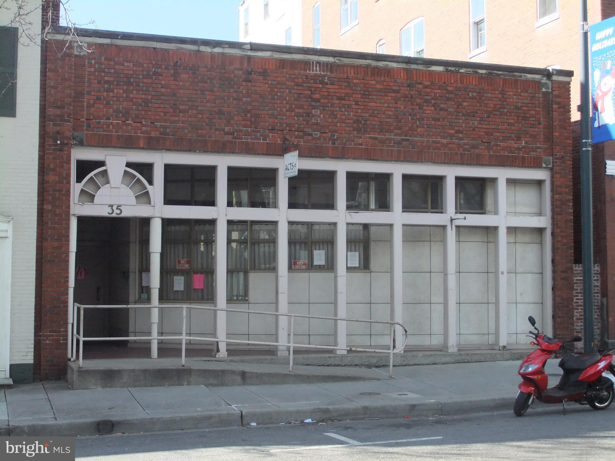Positioned just steps from the heart of Downtown Hagerstown, this commercial opportunity offers approximately 7,800 square feet of above-grade space ideally suited for retail, office, showroom, fitness, entertainment, or specialty commercial use. Strategically located within a two-block radius of the vibrant city core, the property benefits from outstanding walk-ability and accessibility. Nearby amenities include the renowned Maryland Theater, the multi-use recreation facility Meritus Park home to the Hagerstown Suns baseball team, multiple upscale restaurants and retail establishments, professional office buildings, the post office, two public parking decks, and an additional surface parking lot — providing ample parking options for customers and employees alike. The main level features expansive floor space with the front section currently configured with four offices, waiting room, meeting or display areas, a boardroom/library, and a kitchen. The rear section offers a large storage area with excellent flexibility for a variety of commercial layouts and configurations. A mezzanine level includes four private offices, offering additional space ideal for administrative use, private offices, creative studios, or expanded operational needs.
At the rear of the building, a 9-foot drive-through overhead door opens into enclosed open space, creating unique possibilities for loading, secure storage, light distribution, service operations, or adaptable work areas.
With its prime downtown location, versatile layout, and proximity to key attractions and infrastructure, this property presents a rare opportunity for businesses seeking visibility, accessibility, and growth potential in one of Western Maryland’s most active commercial corridors.
