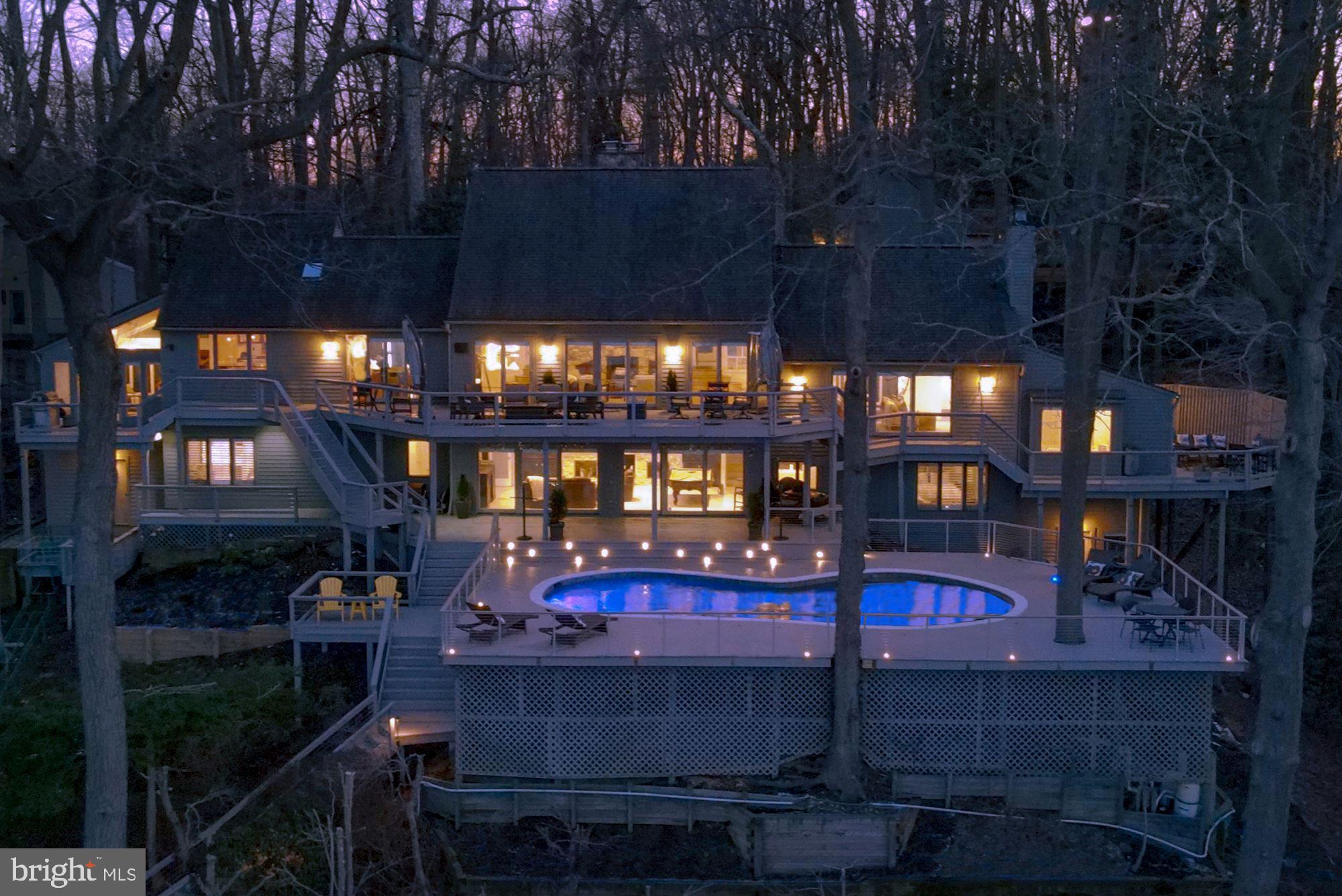 Perched above Hopkins Creek and overlooking Round Bay and the Severn River, this stunning and updated home is sited on almost 1.3 private and waterfront acres. This dramatic and contemporary residence offers an open floor plan with water views from every room and includes everything you could want, both inside and out. The main level features a deck off every room along with a large living room with a river stone fireplace, dining room, sitting area and a gourmet eat-in kitchen with top-of-the-line appliances. Additionally, there is a sunroom, a brand-new, climate-controlled wine tasting room, a powder room and a laundry room. The updated primary suite has a sitting area with a fireplace, office area, luxurious en suite bath with separate jetted tub, shower, & dual vanities, separate walk-in closets, and a private side deck with water views. The lower level features a large family room with fireplace and room for a pool table, two additional bedrooms with en suite baths and ample storage. A separate entry from the rear provides access to an exercise room. Walk out from the lower level to a large updated Trex-type deck featuring the waterside pool and a second deck perfect for enjoying the sweeping water views. Use the stairs or take advantage of the tram down to the private pier. With over 220’ of protected water frontage, the private pier with boat & jet ski lifts offers 6-7’ MLW. A two-car garage has been converted for storage and an additional exercise area, but is easily converted back. There is potential for a guest suite above. Additional parking for 6 cars and generator completes the property. Nestled within Bayberry Hill, this sought-after and gated community is sited on a 70+/- acre private peninsula that offers tennis facilities and an easy commute to Annapolis, Washington, Baltimore and beyond with shopping, restaurants and amenities close by.