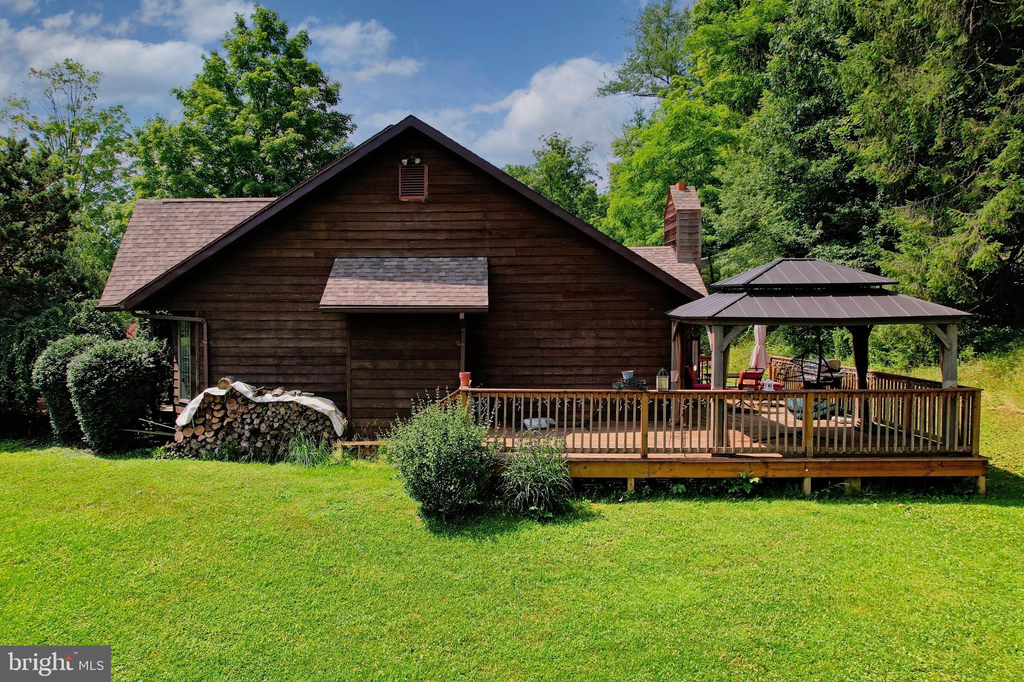 Tucked away on a beautifully wooded 0.65-acre lot, this 1,647 sqdt cedar-sided 4-bedroom, 3-bath home offers a warm and inviting layout with hardwood flooring, a formal dining area, an eat-in kitchen with rich wood cabinetry, center island, gas cooking, and plenty of natural light throughout. The spacious living area features vaulted ceilings, exposed beams, and a stunning stone fireplace that gives the home a cozy lodge-style feel.

Step outside and enjoy the peaceful setting from the covered front porch, private rear deck, and landscaped outdoor spaces surrounded by mature trees. The home also offers multiple living areas, generous bedrooms, a full primary suite, attached 2-car garage, and plenty of room for storage, entertaining, or everyday comfort. If you’re looking for a property with charm, privacy, and a setting that feels tucked away while still being close to town, this one deserves a serious look.