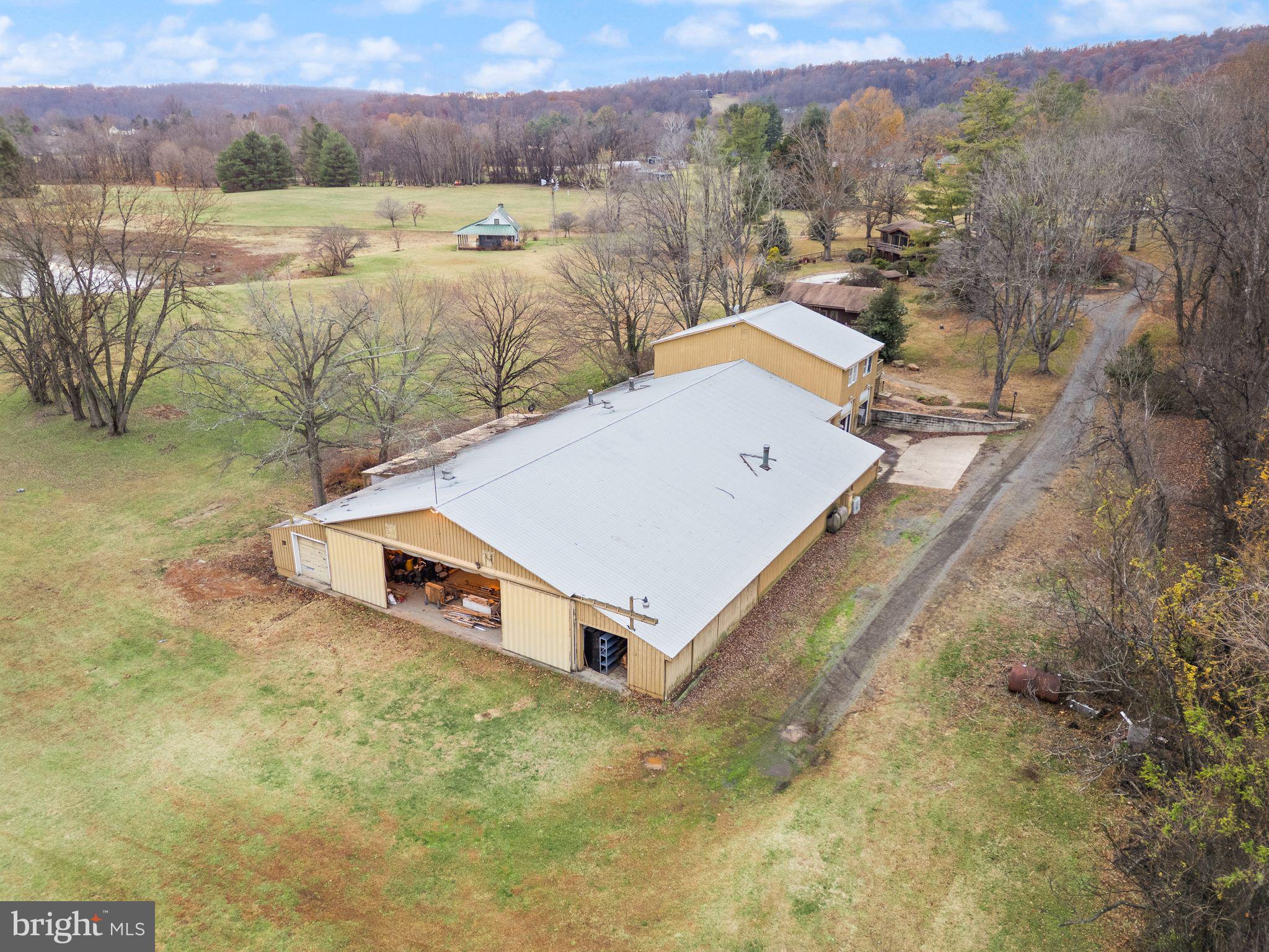 Previously priced without including the fishing shack!!!!!!!  NOW selling the existing home, workout/recreation building, personal storage/workshop building, and fishing shack on a total of 7.45 acres. The pond is not part of the sale.  
A rare opportunity to own a custom mid-century modern home set on a private 7.45-acre parcel in Warrenton, VA—complete with a massive storage/workshop building and a recreation facility featuring a gym/pool house with a full bathroom. This architecturally unique home showcases vaulted wood-beamed ceilings, walls of glass, and open living spaces that seamlessly connect with the natural surroundings. While the home may benefit from updates, it offers exceptional potential in a highly desirable location.

The main level features a dramatic great room with panoramic views, a floor-to-ceiling brick fireplace, and access to an oversized deck—perfect for entertaining or enjoying peaceful sunsets. The open kitchen includes natural wood cabinetry and a center island, offering a solid foundation for modern upgrades.

Also included is a county-approved personal storage/workshop building featuring a second-floor apartment with one bedroom, full bath, full kitchen, and washer/dryer hookups, along with a separate office/library space complete with a full bath and kitchenette. The apartment is approved as a second dwelling (ADU).  

The fishing shack is a truly one-of-a-kind standalone retreat featuring vaulted ceilings, a massive floor-to-ceiling wood-burning fireplace, bedroom loft, kitchenette, and full bathroom. Rustic charm meets cozy comfort, creating the feeling of walking into a Bass Pro Shop lodge tucked away in nature.