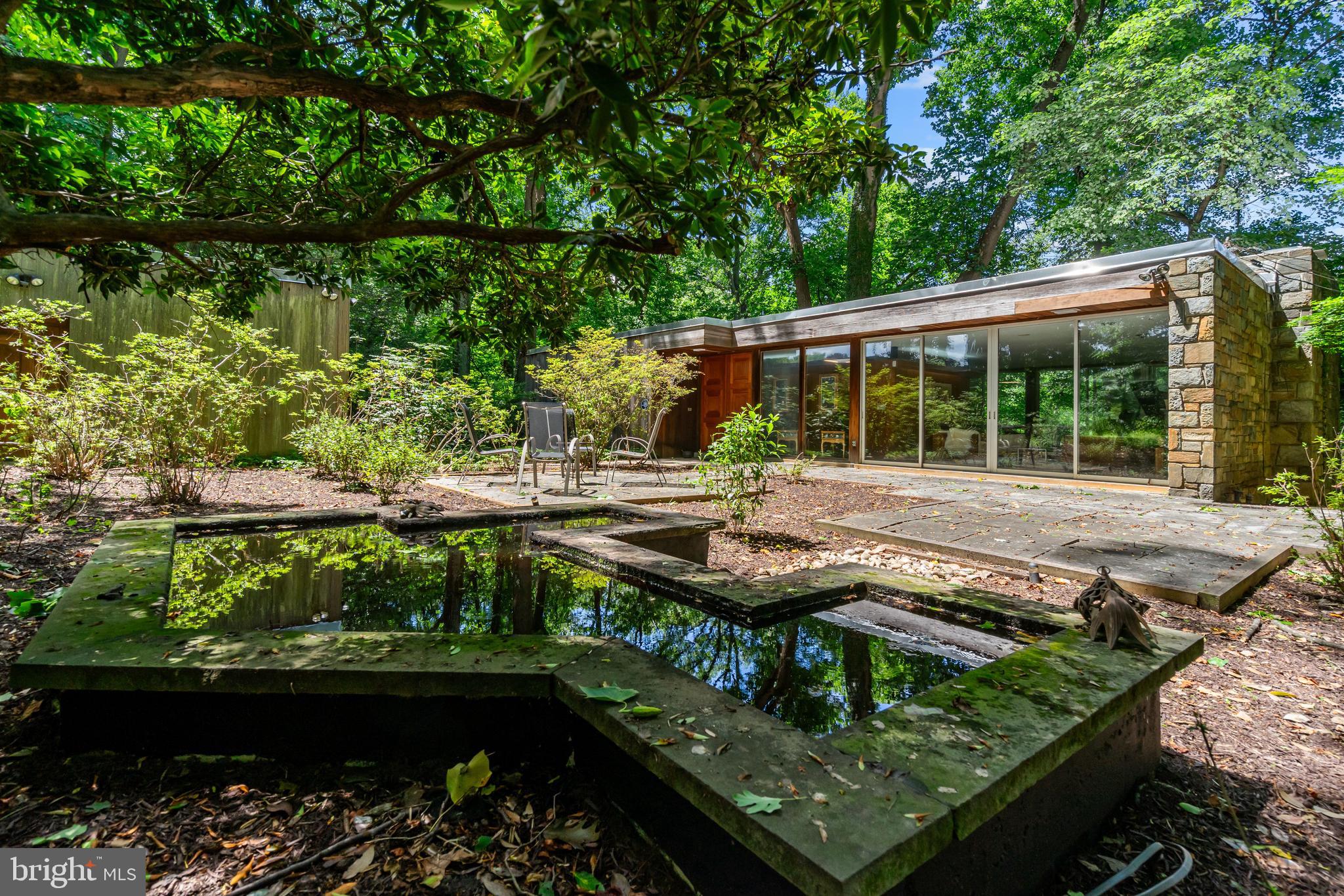 Nestled into the wooded hillside of Rocky Brook Park, 401 Willington Drive is a remarkable custom mid-century modern residence that perfectly captures the designs of Breuer, Johnson and Kahn. Set on more than an acre of wooded, private grounds in Silver Spring, this architectural gem is being offered for sale by its original owners and presents a rare opportunity to own a truly special architectural retreat surrounded by nature.

Inspired by the design of architect Albert Preston Moore’s own home in Greenwich, Connecticut—featured in the April 1959 issue of Architectural Record—the residence, sited on a 1.14-acre lot reflects the clean lines, thoughtful proportions, and seamless indoor-outdoor connection that define the best of mid-century modern design.

Defined by iconic flat rooflines, warm natural materials, and dramatic walls of glass, the home was thoughtfully designed by the Fine family to blur the line between indoors and out. Expansive windows and sliding glass doors frame tranquil woodland views, filling the interiors with natural light and creating a seamless connection to the surrounding landscape.

The stunning main living space is anchored by an extraordinary floor-to-ceiling stone fireplace wall built with local Carderock stone, slate flooring, and expansive glass overlooking the private gardens and mature trees beyond. Rich wood tones, clean architectural lines, and open entertaining spaces create a warm yet sophisticated atmosphere that is both inviting and distinctly mid-century.

A variety of woods are used throughout the house, from the exterior redwood cladding to the original teak cabinets in the kitchen, to the cherry walls, walnut doors, rosewood door handles and oak parquet flooring. The front doors are from the National Gallery of Art while wood rafters were crafted from the bleachers from JFK's inauguration. Customized Shoji screens lend the house a Japanese aesthetic, reflecting the garden design while reinforcing the geometrical priority of mid-century design.

With 5 bedrooms, 2 full bathrooms, and 1 half bath, the home offers exceptional flexibility for modern living, whether hosting guests, working from home, or creating private personal spaces. Radiant heating warms the entire house during winter. A custom detached three-car garage is a rare and valuable addition, offering exceptional space for collectors, hobbyists, or auto enthusiasts while enhancing the home’s private estate-like setting.

The Rocky Brook Park/Quaint Acres area is one of those “hidden gem” pockets of Silver Spring that feels much more wooded and secluded than most close-in DC suburbs.

It’s known for large wooded lots, custom mid-century homes, winding streets, and a strong connection to nature. Many homes were built from the late 1940s through the 1960s, with a notable concentration of custom-designed mid-century modern houses—rather than repetitive tract homes—so no two properties feel exactly alike.

The area borders the wooded stream corridors of the Northwest Branch watershed, giving it a more natural, almost semi-rural feel than many nearby subdivisions. This makes it especially appealing to buyers looking for privacy, mature landscaping, and architecture with character rather than newer subdivision-style homes.

Just minutes from downtown Silver Spring, major commuter routes, and Washington, DC, 401 Willington Drive offers the rare combination of privacy, architectural significance, and everyday convenience—a true hidden sanctuary in one of the area’s most distinctive neighborhoods. (Square footage is approximate and should not be used for property valuation.)