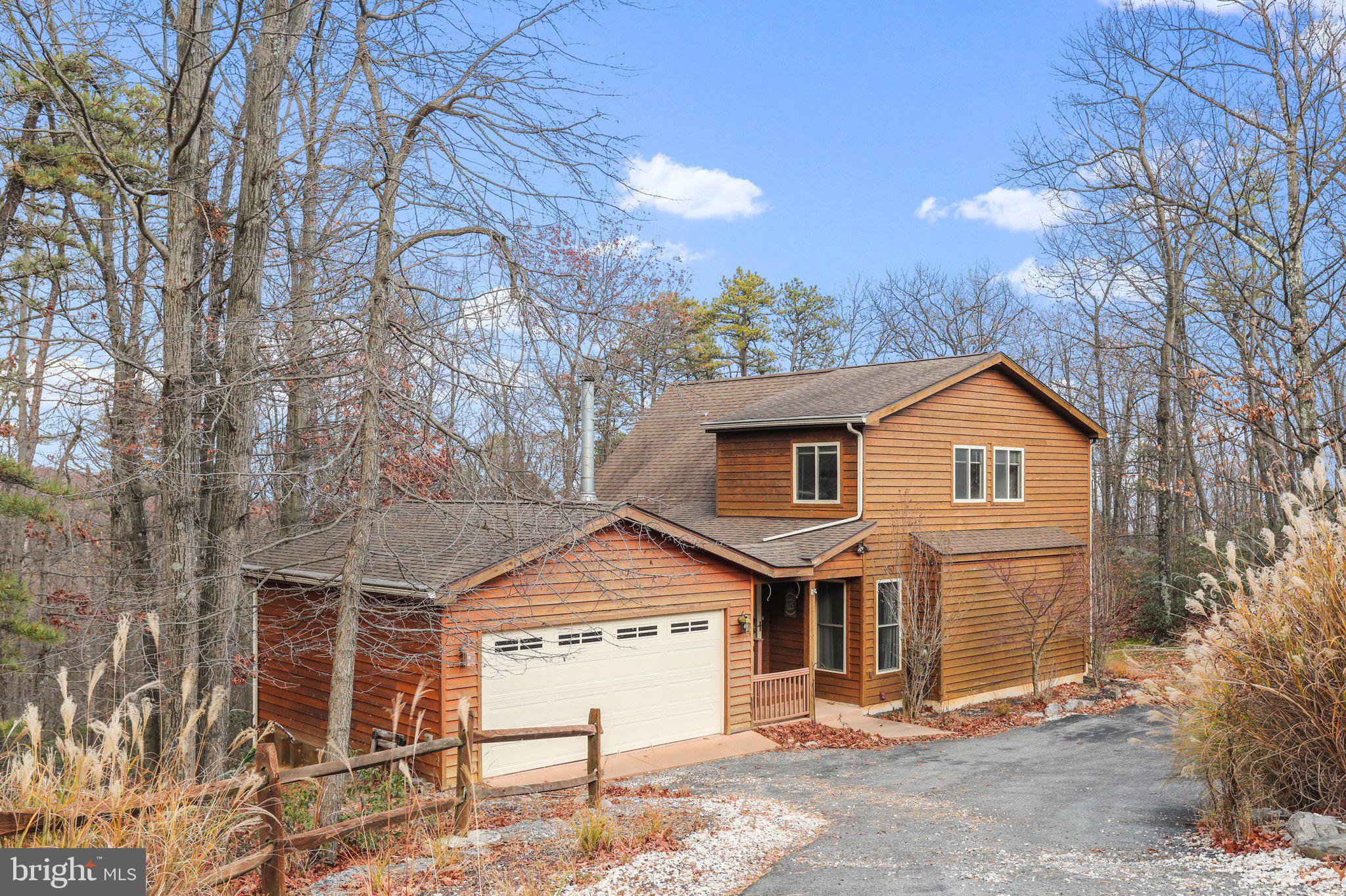 Knock Knock. Come In! Wow, look at that view. This is the perfect mountain chalet. Enjoy the picturesque rock out croppings and the mountain laurel. Amazing private wooded location at The Woods! This home features a wall of windows, sunroom, a loft owners suite, a full walkout basement with a fenced in yard and an attached 2-car garage. If you have been wanting a mountain home, this is it. Cathedral ceilings, exposed wood beams, recessed lighting, and gorgeous wood burning fireplace with stone to the cathedral ceiling and stone hearth are just some of the features in this contemporary open concept A-frame floor plan. You will love to entertain with your family and friends in the open kitchen/great room/dining room. Relax on the 12 x 14 four season room with a cozy gas stove to enjoy on those chilly days. Enjoy all the outdoor nature on the 40x8 attached open deck with wooded views. Lower level features recreation/game room with bar, full bath, craft/office, storage closet, laundry room with shelving and utility room. Paved driveway. Exterior cedar siding and low maintenance timber tech decking makes this home easy to maintain so you can enjoy all the amenities that The Woods has to offer. Membership is available to The Woods Club, Inc. For a Class B with a one time initiation fee of $3,150.00 and annual dues of $1475.00.