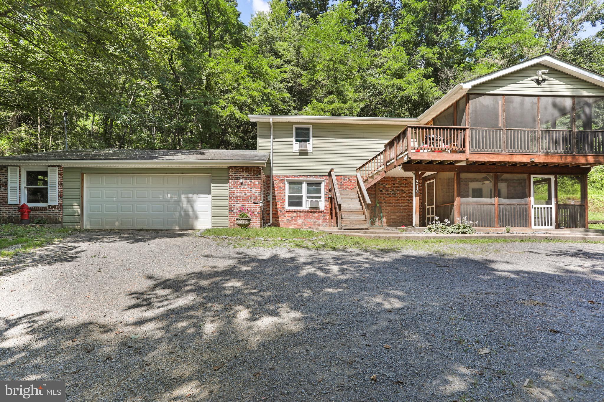 Serene living tucked on 2.61 acres this raised rancher backs to the Cacapon State Park. This charming raised rancher offers the perfect blend of privacy and convenience and less than 30 minutes from Winchester. Featuring 3 Bedrooms and 2 baths this home is designed for comfort. The open concept living area makes it easier to interact more with loved ones and fewer walls offers easier movement and makes the space feel larger.
The basement is fully finished with the main bedroom, bath, laundry and family room. The attached 2 car garage provides plenty of room for vehicles or storage.  You can sip your morning coffee on one of the 2 screened porches or on the back deck while enjoying the peacefulness.