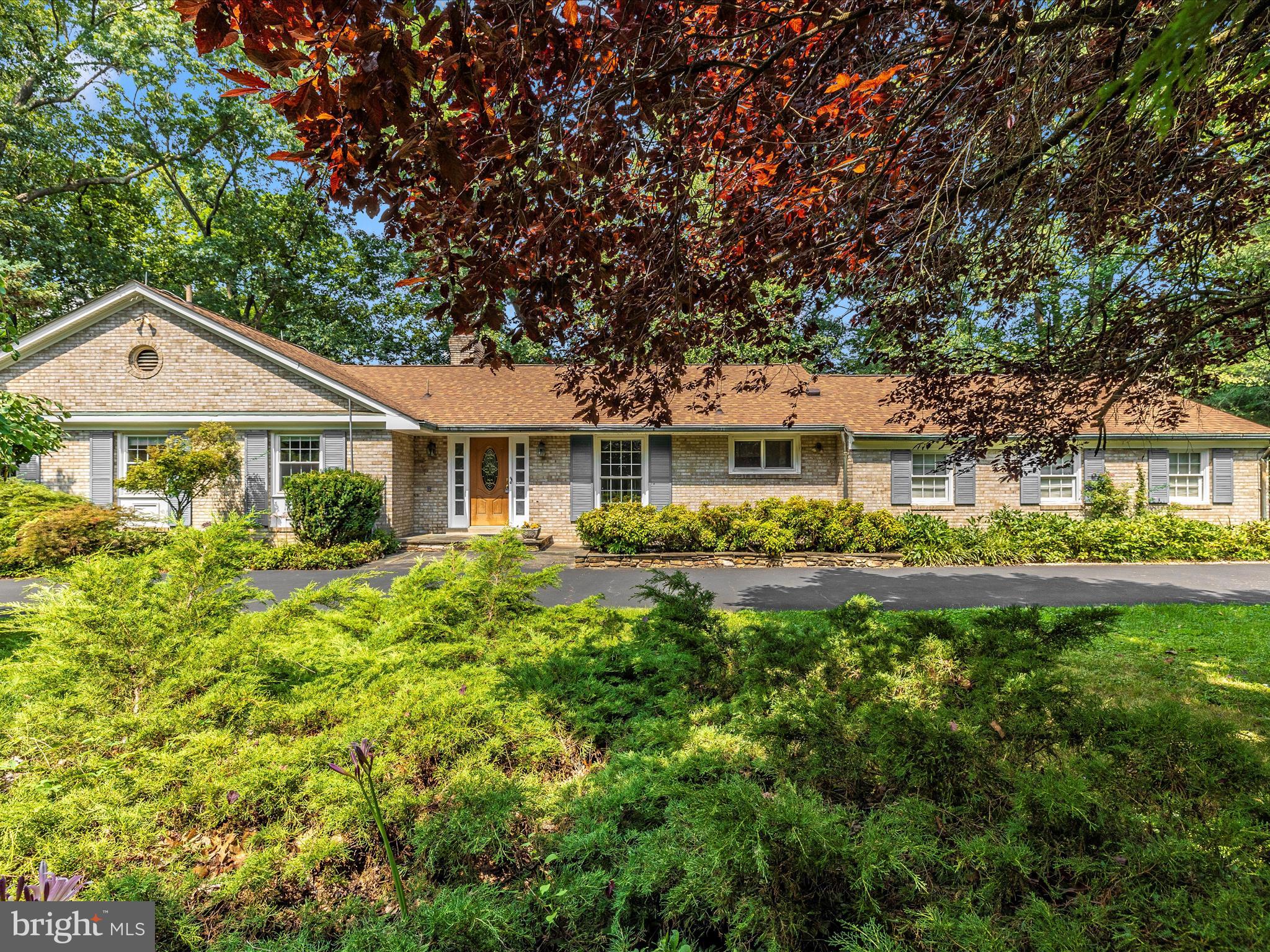 Wonderfully maintained 4 bedroom, 3 bathroom main level living estate that welcomes your arrival via the circular driveway or the side load 2 car enormous garage with overhead storage, workbenches and closet space.  Hardwoods throughout the main level gleam as they have been covered by carpet for many years.   A serene sunroom balances the private rear of the home with its own gas stove for cozy appeal and an overhead dedicated mini split heating and air conditioning system.  A large living room, dining room and family sized eat in kitchen are just off the oversized garage.  3 large bedrooms and 2 full baths with an ensuite laundry complete the large first floor.  Amenities include incredible mature landscaping, decks, peaceful and calming gardens, a gorgeous waterfall, sitting benches, trails through the hardwoods and butterfly bushes.  All major renovations include a 2019 roof,  gutter system, copper gutters and downspouts, new chimney flue liners and squirrel/bird cages, new natural gas hot water heater, newer gas furnace and heat pump comfort systems (2021), mini split system in sunroom,  new 2022 refrigerator, septic completely redesigned and upgraded (2022, also pumped).  The upstairs windows have all been replaced.    Gas logs in the lower level rec room where you will find an additional bedroom and full bath, a walkout entrance/exit in 2 places, a large well organized usable utility room and a 2nd laundry.  The rec room is HUGE with a built in bar and a very large storage room with its own closet.  Once outside, the grounds are entirely and truly captivating.  There are so many relaxing areas and with the lake so close, bird and nature enthusiasts will be in heaven!  This one is so special and will welcome you HOME!