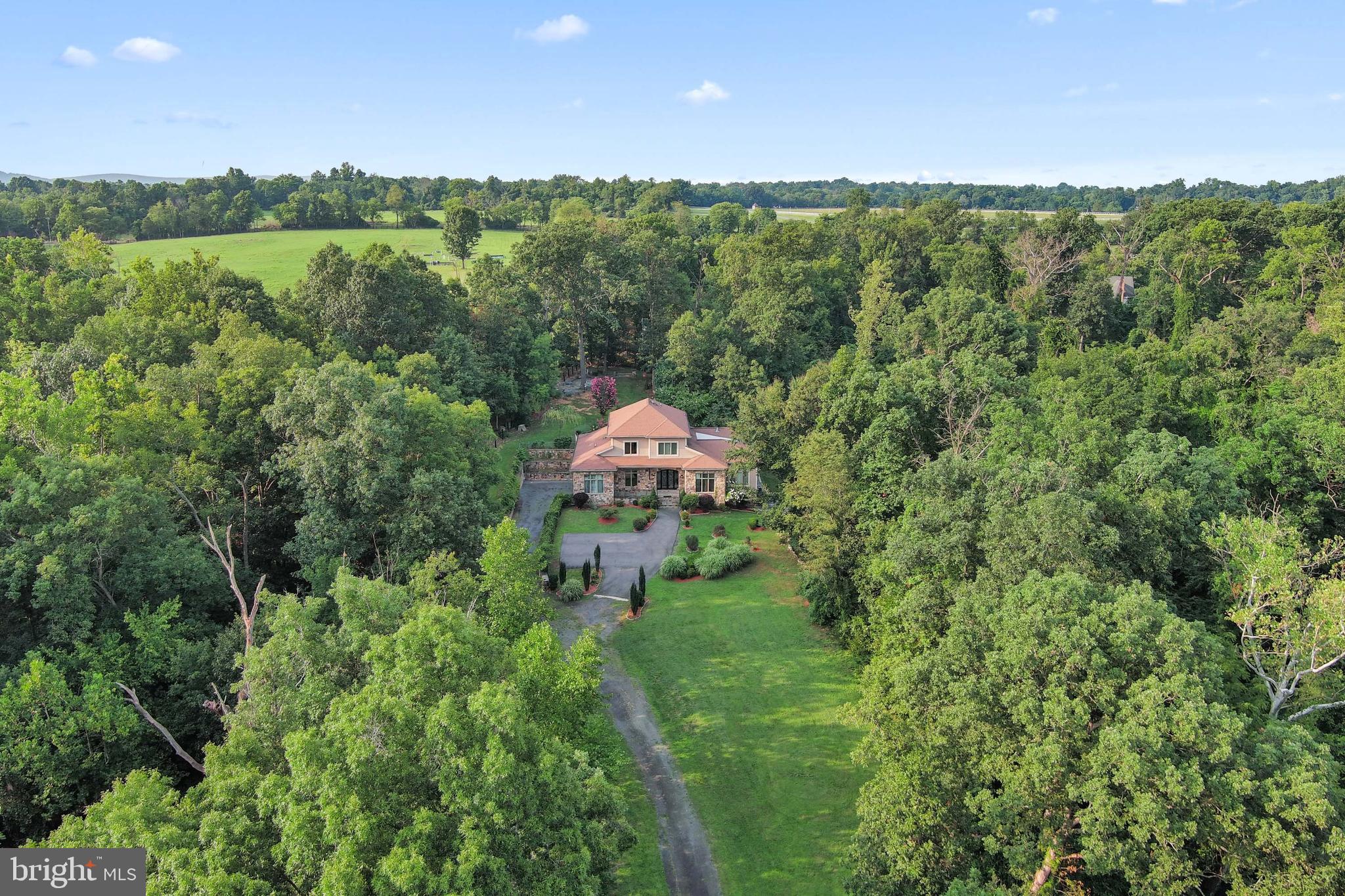 Designed for both refined entertaining and privacy, this incomparable property captures the essence of Virginia's hunt country with dramatic Blue Ridge Mountain views, mature oak trees, and bold streams creating a private sanctuary. The entertainer's paradise unfolds across 10.76 acre and 7,172 square feet of elegant living space featuring exquisite craftsmanship and seamless indoor-outdoor flow. Nature and luxury converge in perfect harmony with an expansive terrace leading to an opulent backyard oasis of expansive greenery and custom bar entertainment area. A screened-in veranda overlooks panoramic nature views. The luxurious primary suite offers unparalleled privacy with two generous closets, a freestanding soaking tub, and a private balcony overlooking the picturesque landscape. The open-concept kitchen features custom double-door walk-in cabinetry, uniting elegant design with effortless organization. Fresh well water flows through a comprehensive home filtration system with softener and reverse osmosis for drinking. Just minutes from historic Middleburg's charm, this exceptional estate presents an unparalleled opportunity to create a landmark family compound with no HOA restrictions and an additional building site available, enhancing future flexibility.