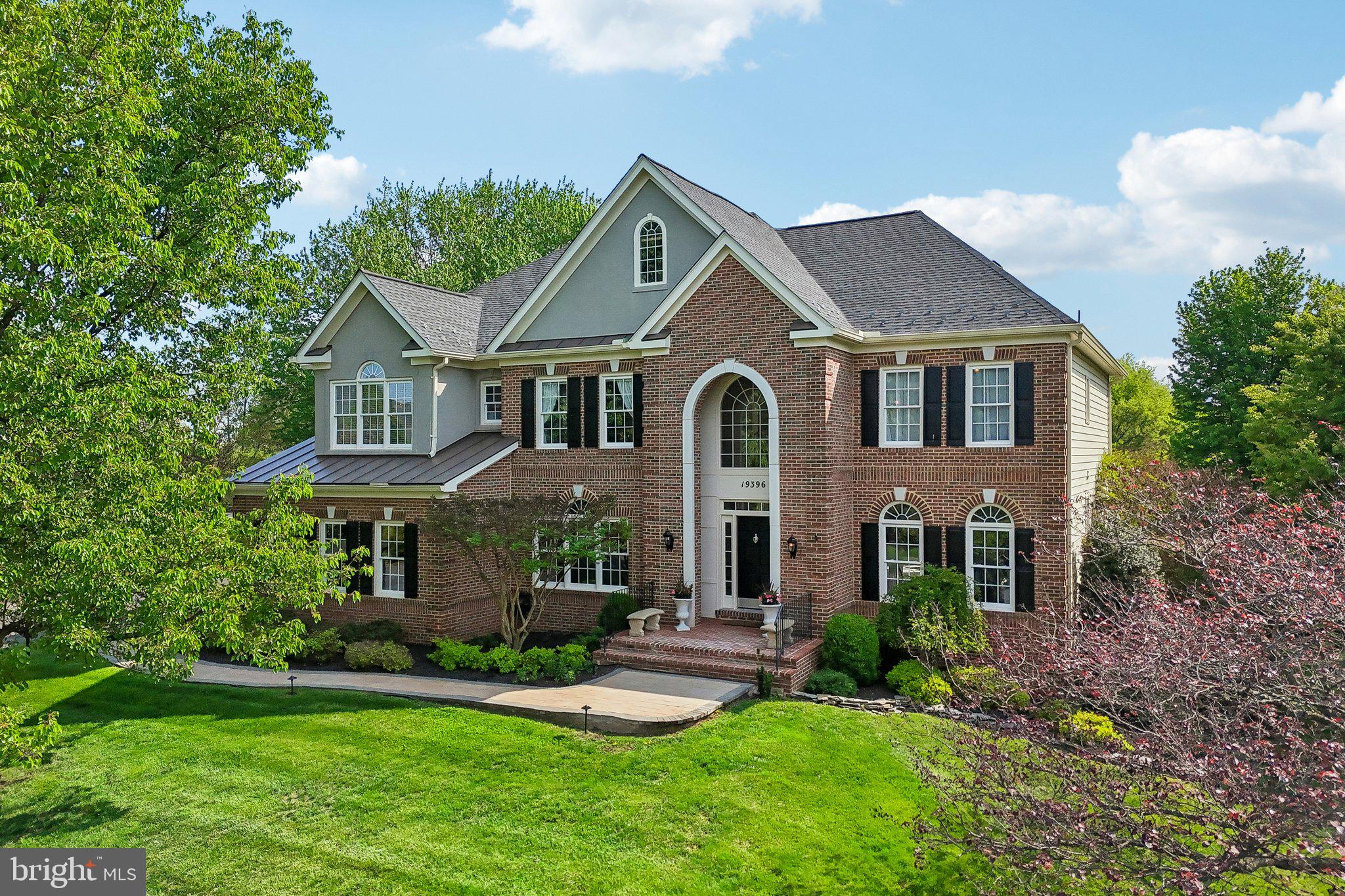 A rare opportunity to own a true turnkey estate in Leesburg's coveted Emerald Park — 3.1 private acres fully enclosed by an oak wood fence, 7 bedrooms, 4.5 bathrooms, and over 6500 square feet of extensively renovated living space. Manicured grounds with mature canopy trees, garden pond, multi-level composite deck, lower gravel and flagstone patio, 3-car garage, generator hookup, and EV charging circuit installed.
The grand two-story foyer sets the tone: crystal chandelier, tray ceiling, and upgraded iron-and-wood staircase. The main level flows from formal living and dining into a dramatic two-story family room anchored by a floor-to-ceiling stone fireplace, soaring arched transom windows, and an elegant wainscoting panel accent wall, connecting directly to an expansive sunroom with five signature arched windows, large format marble-look porcelain flooring, and rear deck access.
The estate-scale kitchen features dual furniture-grade islands, granite countertops, a KitchenAid appliance suite with double wall ovens, elegant backsplash, crystal pendant lighting, and a butler's pantry.
A main-level library and office offers floor-to-ceiling custom dark built-ins with rolling ladder and a window framing the tree-lined backyard.
The primary suite features a $70,000 bathroom renovation: marble wall and flooring, frameless glass rain shower, freestanding soaking tub, dual-sink custom vanity with champagne bronze hardware, and dual backlit LED mirrors. Two custom walk-in closets complete the suite. Upper level includes 5 bedrooms and 3 full baths, including a Jack & Jill layout. New hardwood floors on the upper level and staircase, crown molding throughout main and upper levels.
Over $350,000 in improvements: HVAC, humidifier, UV air purification, water treatment, drainage, gutters, renovated bathrooms, and custom closets.
The finished walkout lower level offers a home gym, media/game area, wet bar, two bedrooms, and renovated full bath — ideal for extended living.