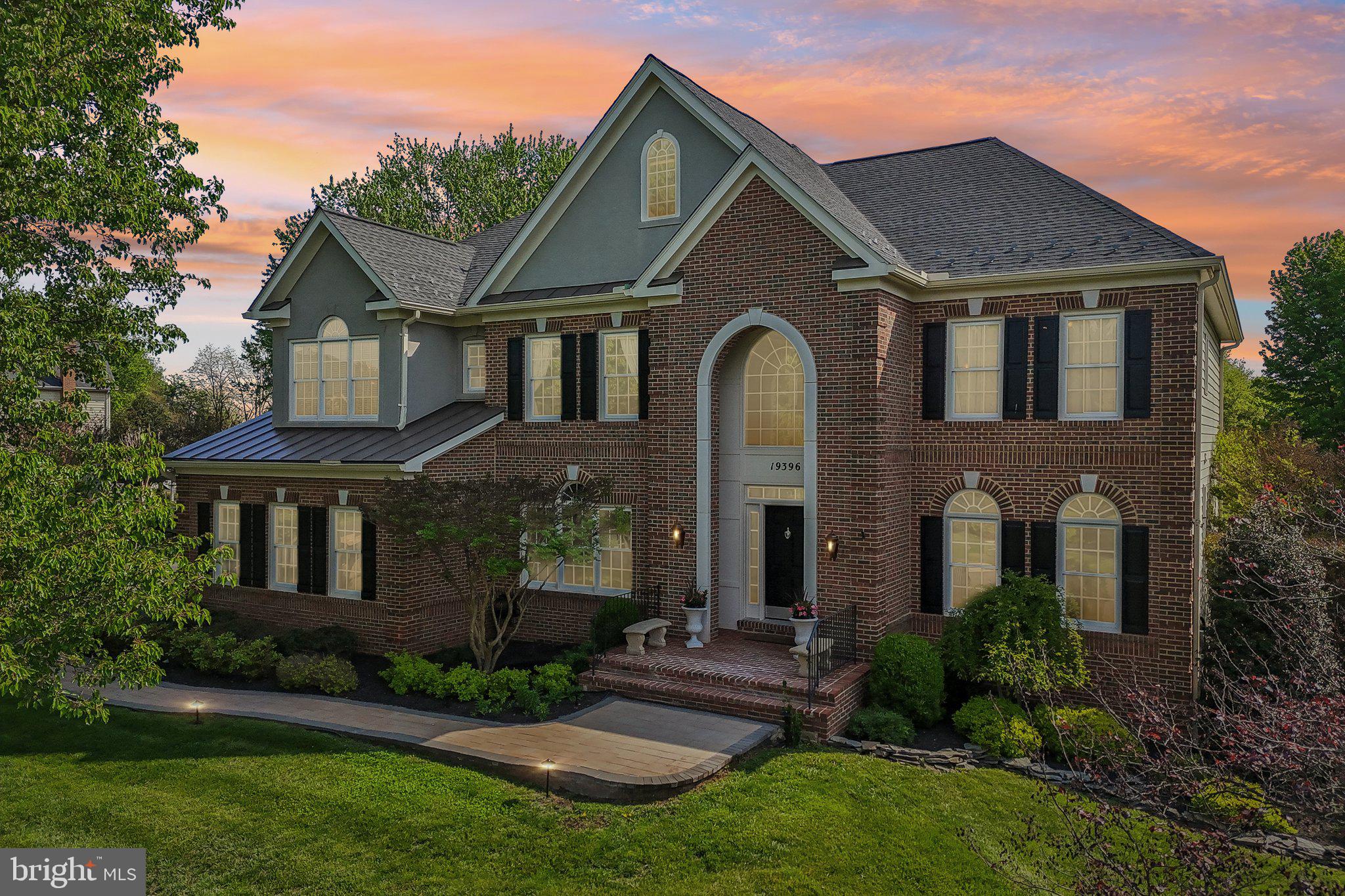 A rare opportunity to own a true turnkey estate in Leesburg's coveted Emerald Park — 3.1 private acres fully enclosed by an oak wood fence, 7 bedrooms, 4.5 bathrooms, and over 6500 square feet of extensively renovated living space. Manicured grounds with mature canopy trees, garden pond, multi-level composite deck, lower gravel and flagstone patio, 3-car garage, generator hookup, and EV charging circuit installed.
The grand two-story foyer sets the tone: crystal chandelier, tray ceiling, and upgraded iron-and-wood staircase. The main level flows from formal living and dining into a dramatic two-story family room anchored by a floor-to-ceiling stone fireplace, soaring arched transom windows, and an elegant wainscoting panel accent wall, connecting directly to an expansive sunroom with five signature arched windows, large format marble-look porcelain flooring, and rear deck access.
The estate-scale kitchen features dual furniture-grade islands, granite countertops, a KitchenAid appliance suite with double wall ovens, elegant backsplash, crystal pendant lighting, and a butler's pantry.
A main-level library and office offers floor-to-ceiling custom dark built-ins with rolling ladder and a window framing the tree-lined backyard.
The primary suite features a $70,000 bathroom renovation: marble wall and flooring, frameless glass rain shower, freestanding soaking tub, dual-sink custom vanity with champagne bronze hardware, and dual backlit LED mirrors. Two custom walk-in closets complete the suite. Upper level includes 5 bedrooms and 3 full baths, including a Jack & Jill layout. New hardwood floors on the upper level and staircase, crown molding throughout main and upper levels.
Over $350,000 in improvements: HVAC, humidifier, UV air purification, water treatment, drainage, gutters, renovated bathrooms, and custom closets.
The finished walkout lower level offers a home gym, media/game area, wet bar, two bedrooms, and renovated full bath — ideal for extended living.