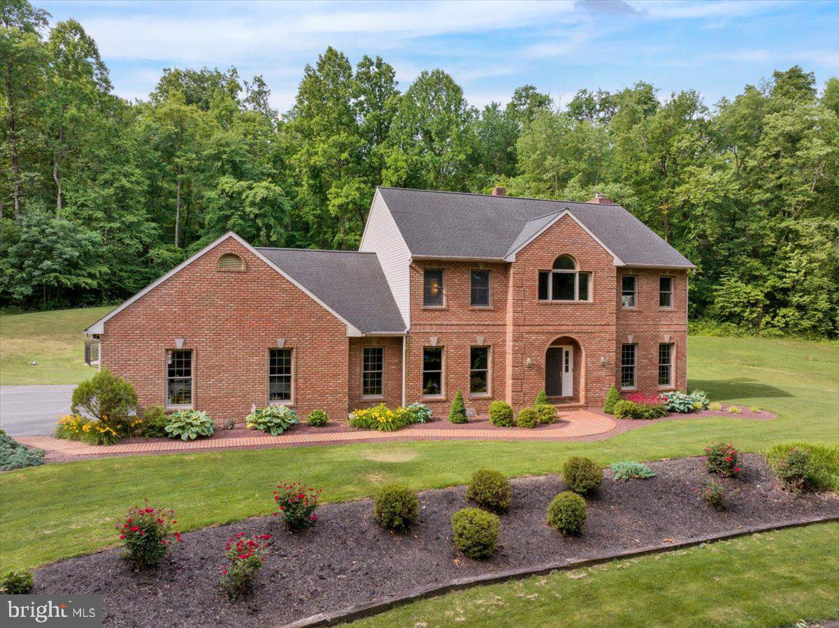 Welcome to 415 Greenville Road, a truly one-of-a-kind custom brick estate nestled on 10.8 private acres in the highly sought-after Cocalico School District.  Hidden at the end of a paved 500-foot driveway and surrounded by mature landscaping, this exceptional property offers complete privacy while remaining just minutes from the PA Turnpike and Routes 222 and 322.  Built with quality and efficiency in mind, this custom home features 2x6 construction, Andersen windows, geothermal HVAC, luxury vinyl plank flooring throughout, and an oversized three-car garage complete with an EV charging station.  The thoughtfully designed floor plan offers four bedrooms and 3.5 bathrooms, including a luxurious primary suite with a large walk-in closet and a recently renovated spa-inspired bathroom.  The heart of the home is the beautifully appointed kitchen featuring granite countertops, custom Conestoga cabinetry, and a center island that provides additional seating along with the formal dining area, perfect when hosting larger gatherings.  The kitchen transitions nicely to the spacious living room with a vaulted ceiling and stone fireplace with a wood-burning insert.  A dedicated first-floor home office provides the perfect work-from-home setup, while an additional full bathroom with convenient exterior access is ideal for guests enjoying the pool.  Step outside to your own private resort featuring a spectacular 35,000-gallon heated concrete swimming pool, an oversized hot tub, expansive outdoor entertaining areas, and endless opportunities to relax and unwind.  Explore your own ATV and hiking trails throughout the wooded acreage, all while benefiting from the property's enrollment in the Clean and Green program.  Additional outbuildings include a detached two-story brick garage/workshop, a 12' x 25' utility building, and a woodshed, providing exceptional space for hobbies, storage, or recreational equipment.  This remarkable property truly has it all: quality craftsmanship, energy-efficient construction, unmatched privacy, and room to enjoy the outdoors.  A rare opportunity to own a custom estate where every day feels like a getaway!