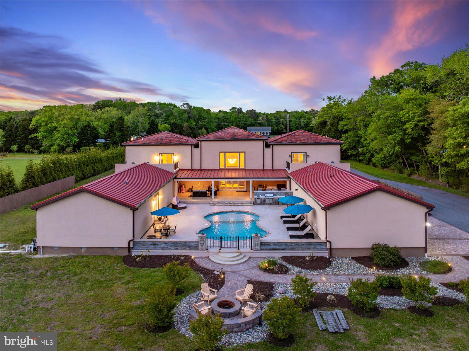 Property Overview: Residence: 6,800 SF  |  3-Car Garage: 1,200 SF  |  Warehouse/Flex Building: 3,100 SF
Pool Deck: 3,500 SF.............Set across 18+ private acres in Bishopville, this estate is a study in scale, discretion, and purposeful design—an offering rarely seen this close to Ocean City and the Delaware coastline. The residence spans 6,800 square feet of curated living space, where proportion and restraint define the experience. Elevated ceiling heights, clean architectural lines, and a cohesive material palette create an environment that feels both expansive and composed. At its center, the kitchen is executed with precision—Silestone quartz surfaces, custom Wolf cabinetry, and a substantial island designed for both function and gathering. Every element has been selected for performance, longevity, and understated elegance. The home unfolds into a series of well-scaled living and entertaining spaces. The primary suite is quietly refined, offering tailored storage and a sense of retreat. Throughout, the emphasis is on livability without compromise. Beyond the residence, a 3,100-square-foot warehouse/flex structure introduces a level of versatility seldom found in residential offerings. With separate access, dedicated utilities, and a blend of finished and open space, it accommodates everything from a private studio or executive workspace to collector-grade storage. Outdoors, the estate transitions seamlessly into a resort-caliber setting. A heated saltwater pool is framed by an expansive 3,500-square-foot deck, complemented by a fully integrated outdoor kitchen and fire feature—designed for effortless entertaining and quiet evenings alike. Infrastructure is equally considered. Enhanced electrical capacity, specialized equipment readiness, and engineered drainage systems ensure the property performs at the highest level behind the scenes.
Clad in timeless, low-maintenance materials—including stucco/EIFS, Andersen windows, and a blend of standing seam metal and composite barrel tile roofing—the exterior reflects the same commitment to longevity and design integrity. This is not simply a residence—it is a private compound offering scale, flexibility, and proximity to the coast, without sacrificing privacy or control.