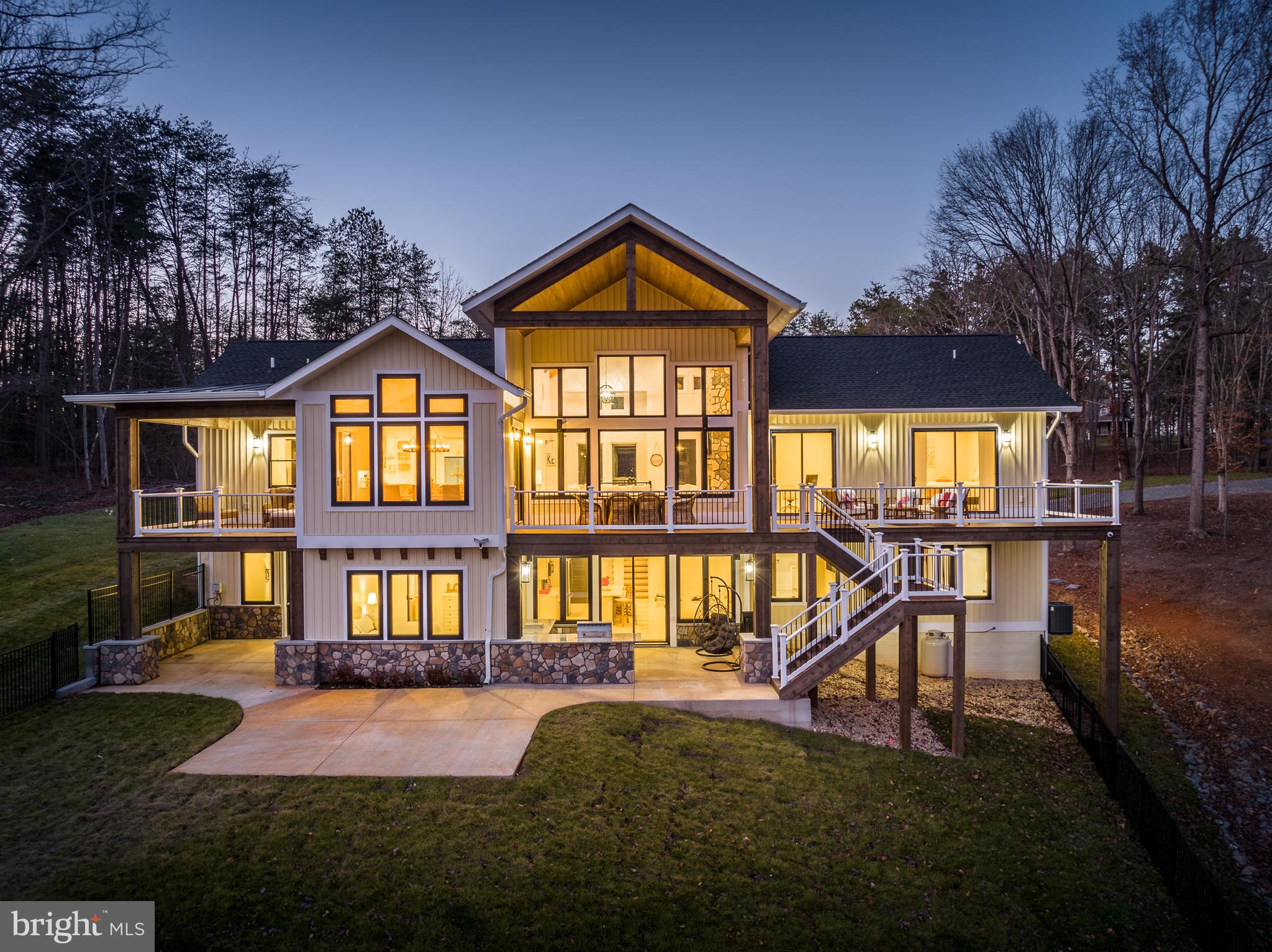 A stunning waterfront masterpiece, this newly constructed custom oasis offers a spectacular and rare opportunity set upon the beautiful shores of Lake Anna, Virginia.  Truly unrivaled in quality and design, this impeccably crafted escape blends modern luxury living with tranquil lake lifestyle.  Encompassing over 5,000+ square feet on two open levels, this paradise offers seamless indoor/outdoor lakeside living, with 5 bedrooms, all with custom designer full baths, 2 additional half baths, a quiet office with water views, a tremendous back deck living area constructed from composite decking also overlooking the water, wirelessly controlled indoor/outdoor home stereo system, two covered lakeside porches, a giant 1,400 finished square foot 3+ car garage, and over 150+ feet of private shoreline down at the water’s edge.  Step inside into a sunny open floor plan, featuring floor-to-ceiling windows that showcase jaw-dropping water views of Lake Anna, soaring beamed ceilings, a warm fireplace with gorgeous floor to ceiling stone, and crisp maple engineered hardwood flooring.  The main floor is punctuated by very high ceilings and majestic 8-foot doors.  The bright gourmet kitchen supplies high end designer appliances by Big Chill, smooth quartz countertops, oversized glass pendant lights that levitate weightlessly above the massive island, under cabinet lighting, and beautiful custom tile work beneath your feet.  The cozy dining area overlooks the public side of Lake Anna.  The oversized primary bedroom suite is located on the main level as well, with its own private access to the large deck overlooking the lake, a massive walk-in closet and en suite primary bathroom with incredible custom tile work, stand alone claw foot tub, separate tile shower and two separate vanities.  The other end of the main level includes a spacious bedroom with water views, a half bath and a mudroom with laundry and a custom tile dog shower.  Downstairs in the expansive walkout basement, you’ll find bright white tile floors, a gorgeous bar & kitchen entertainment area, family room, three bedrooms, and two additional bathrooms with incredible custom tile work and designer hardware.  Advanced smart-home system (Wifi-controlled cameras, speakers, thermostats, garage doors, integrated Cat 6 cabling throughout, and exterior security lighting).  Walk outside to the covered, brand new outdoor stone kitchen and patio.  A few steps away at the water, you’ll enjoy warm summer days down at your very own boathouse with electric boat lift, storage area and swim/sun deck.  Perfectly nestled on a deep water cove for swimming.  The house also features another bathroom only accessible from the outside, convenient for those outside entertainment days.  Brand new designer furniture can convey with purchase.  Short-term rentals permitted.  Perfect central location on the lake; just 5 minutes from groceries, restaurants, the Lake Anna Taphouse and more.