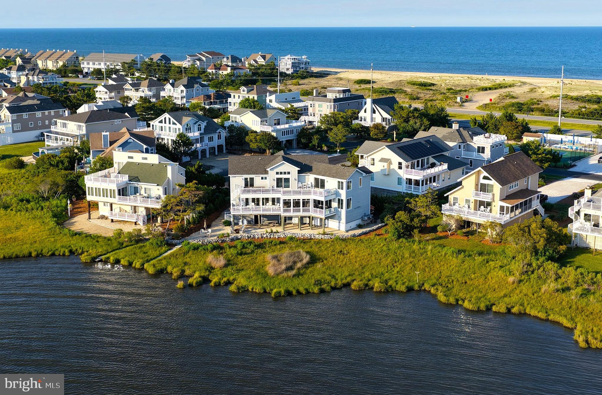 Perfectly positioned along the bay just moments from the beaches of Fenwick Island, this extraordinary waterfront residence captures breathtaking panoramic water views from nearly every room. Wake to spectacular sunrises over the ocean, spend the day watching coastal wildlife and boating activity on the bay, and unwind each evening with unforgettable sunsets from the comfort of home. Beautifully renovated, professionally decorated, and impeccably maintained, this turnkey residence seamlessly blends timeless coastal elegance with today's finest luxuries. An elevator provides effortless access to every level, enhancing both comfort and convenience. Designed to showcase its exceptional waterfront setting, the main living level features an expansive open-concept floor plan where walls of glass frame the ever-changing bay views. At the heart of the home, the gourmet kitchen is both stunning and highly functional, featuring custom cabinetry, gleaming quartz countertops, an oversized center island, premium stainless-steel appliances including double wall ovens, an elegant beverage station, abundant storage, and generous prep space. The kitchen flows effortlessly into the dining area and great room before extending to a spacious waterfront screened porch and sun deck, creating exceptional indoor-outdoor living for both intimate gatherings and grand entertaining. Just beyond the kitchen, a welcoming family room provides a comfortable secondary gathering space. The main level also offers one of six private ensuite bedrooms, along with an additional full bath for guests. The upper level is anchored by a spectacular bayfront owner's retreat featuring a private office and direct access to an expansive waterfront deck—the perfect setting for morning coffee, evening cocktails, or simply taking in the sweeping water views. Four additional ensuite bedrooms, each thoughtfully designed to capture beautiful water vistas, provide exceptional comfort and privacy for family and guests. Outdoor living is equally impressive. Multiple waterfront decks, a spacious screened porch, firepit, and beautifully landscaped grounds create inviting spaces to relax, entertain, and embrace the coastal lifestyle. The oversized, fully insulated two-car garage features extensive built-in cabinetry and also serves as an ideal game room or recreation space. After a day at the beach, two outdoor showers with private changing areas provide the perfect place to rinse away the sand before returning indoors. Located just north of the Town of Fenwick Island in the highly sought-after community of Seatowne, residents enjoy an exceptional collection of resort-style amenities, including a swimming pool, tennis and pickleball courts, and a bayside pier ideal for launching kayaks and paddleboards. Offering an unparalleled combination of refined luxury, breathtaking water views, exceptional craftsmanship, and effortless access to both the bay and the beach, this remarkable residence presents a rare opportunity to own one of the Delaware coast's most exceptional waterfront homes.