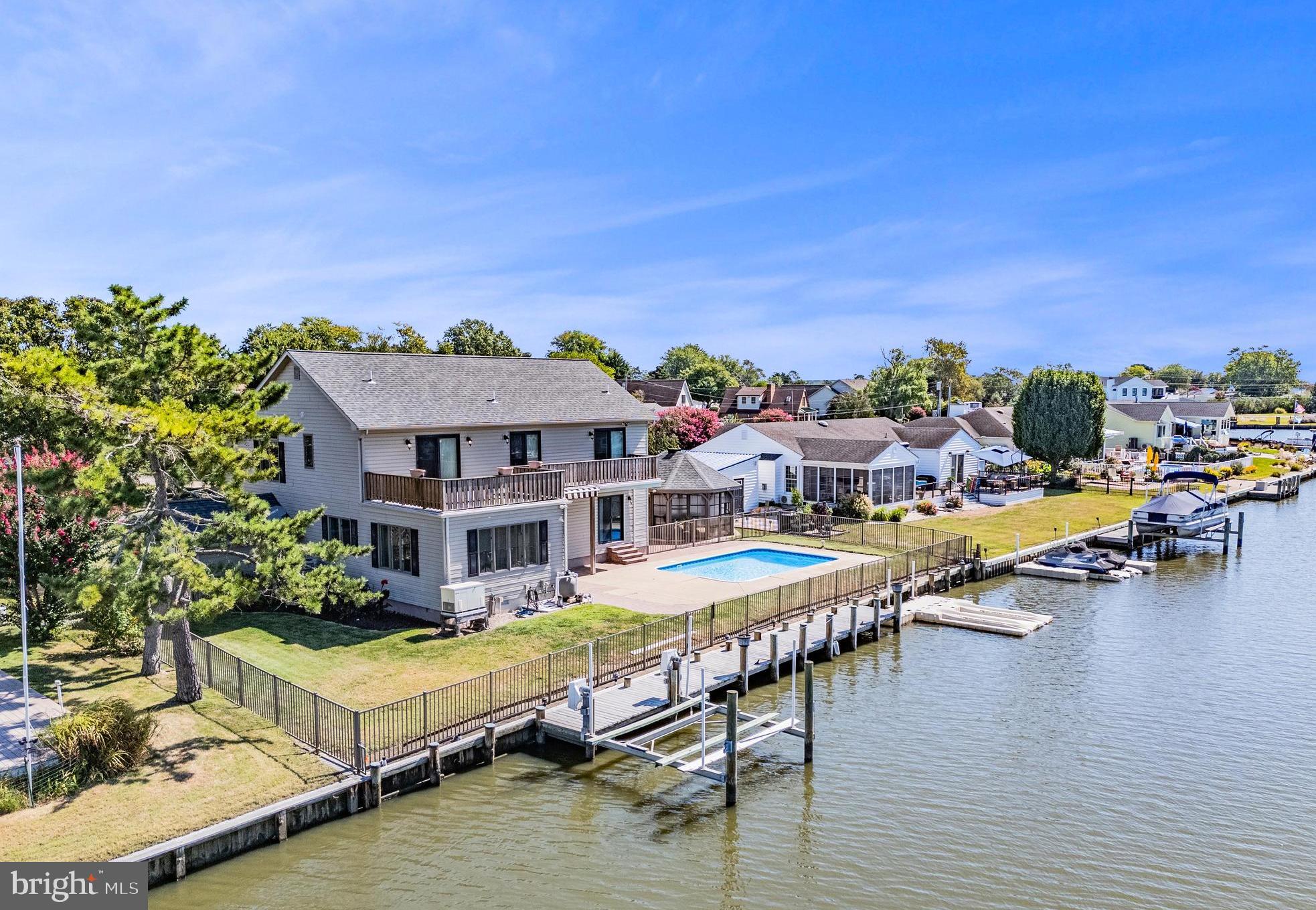 REHOBOTH BAY ESCAPE: DOCK, POOL AND SCENIC WATER VIEWS!
This is the one you've been waiting for. A private dock with boat lift, in-ground pool, screened gazebo, and easy access to Rehoboth Bay; all in one exceptional waterfront package.
Inside, the dramatic great room sets the tone with vaulted ceilings, skylights, gleaming hardwood floors, and a gas fireplace perfect for cool coastal evenings. The open-concept layout flows seamlessly into the updated kitchen, featuring white cabinetry, granite countertops, a center island with bar seating, mosaic tile backsplash, stainless steel appliances, and a bonus built-in wine fridge. The thoughtful floor plan also offers a first-floor bedroom with private en suite bath, ideal for guests or multigenerational living. Upstairs, three additional bedrooms all enjoy direct access to the upper-level deck and balcony, where bay breezes and water views are yours morning and night.

With a two-car garage, generous square footage, and a layout that lends itself to strong vacation rental investment potential, this property is as practical as it is impressive just minutes by car or boat to Rehoboth Beach, the boardwalk, shopping and dining!

Boat. Swim. Relax. Repeat. Call today and have it by summer!