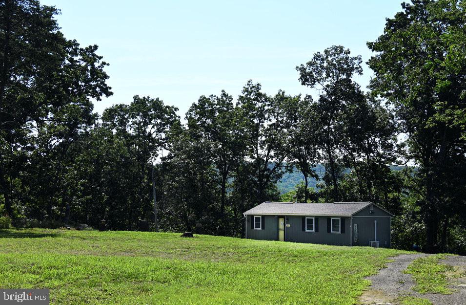 Embrace the tranquility of mountain living in this charming West Virginia retreat. Nestled on a private, wooded lot in Hampshire County, this property offers a perfect blend of secluded country living and easy access to local conveniences. This well-maintained cabin features a comfortable, open common space, a fully equipped kitchen, two bedrooms, and one full bathroom. A large, open-air patio extends your living space outdoors—ideal for relaxing with family or entertaining guests. 
    The home is being offered fully furnished, allowing you to settle in or start hosting immediately. The comprehensive sale includes an array of essential property maintenance and outdoor living items including a storage shed, backup generator, security camera system, log splitter,  garden trailer, Blackstone grill, and two riding lawn mowers. 
  This region offers a perfect balance of nature and urban convenience, featuring multiple state parks within a one-hour drive and Washington, D.C., just a two-hour drive away. The property grounds are diverse and self-sustaining. Please note that there are active bee hives located on the lower section of the property near the camper. Whether you are looking for a weekend getaway or a permanent residence, this move-in-ready mountain escape is prepared for its next owners.