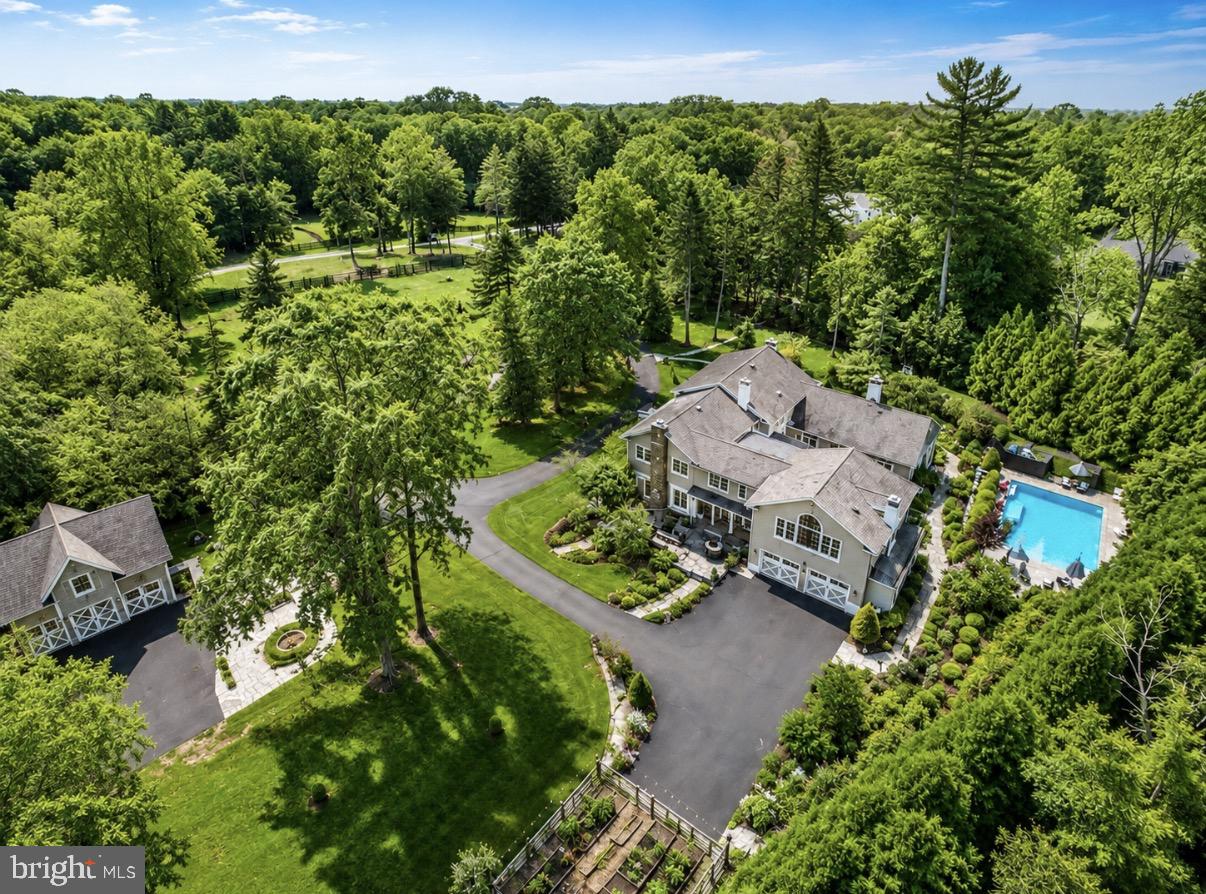 Accessed through an exclusive, private gateway, 1087 Mt Eyre Road is an impressive estate nestled within the historic district of Washington Crossing, spread over 3.5 acres of beautifully landscaped grounds. This incredible residence showcases over 6,000 square feet of spacious living area, robust infrastructure, and intricately designed outdoor spaces, all within close proximity to the area's charming river towns.  Enveloped by lush greenery, carefully manicured rose terraces, and a secure iron-fenced border, the property delivers a sense of magnificence and grandeur. The heart of the estate is a stunning courtyard with a heated pool, offering an authentic estate feeling, while maintaining a welcoming and livable ambiance. The property exudes comfort and is ready for immediate occupancy; however, it is thoughtfully priced to allow future owners the opportunity to infuse their unique style and vision over time.  Internally, the home presents oversized rooms dressed with hardwood flooring, stained-glass windows, crown molding, and the charm of four fireplaces, encapsulating warmth and character throughout. The gourmet kitchen boasts ornate cabinetry and is a true chef's delight, engineered for practicality and social gatherings. The space features dual ovens, two dishwashers, two concealed Sub-Zero fridges, cooling drawers, a built-in Bosch espresso machine, a coffee station, a vented cooktop, a voluminous island with a double sink, and impressive natural light from the surrounding windows.  An expansive dining room caters to substantial social events, while a freshly painted den, adorned with a wood-burning fireplace, offers a more intimate setting. The magnificent great room features another fireplace, a fully equipped bar, and doors that open onto the patio and courtyard. The main level also encompasses a formal sitting room, a private office, a conveniently located powder room with pool access, and a combined utility and mudroom with an additional Sub-Zero fridge. Upstairs,  the generosity continues with exceptionally large bedrooms and versatile living areas. The Owner's Suite showcases dual vanities, a steam shower, a Jacuzzi tub, a walk-in closet, and a romantic private balcony overlooking the pool and picturesque gardens, complete with spiral staircase access to the ground level.  Impossible to miss, the outdoor setting mirrors a luxurious resort, boasting a heated pool and hot tub, a built-in grill, multiple patios, and meticulously maintained rose gardens. Modern amenities include a property-wide irrigation system, a comprehensive water filtration system, four-zone HVAC, 100 owned solar panels, a new pool heater, and two Tesla Powerwalls, ensuring the home's efficacy and sustainability. An integral, two-vehicle garage is perfectly supplemented by a detached three-car garage, boasting a fully-equipped gym overhead. This unique configuration presents an outstanding level of versatility, suitable for fitness, artistic pursuits, workshop activities, or for those with a penchant for collecting. Advantageously situated in close proximity to the communities of New Hope, Lambertville, and the picturesque riverside locales of Bucks County, the property affords easy access to New Jersey and provides a convenient commute to New York City. The impressive scale of this estate,  its robust infrastructure, and the rare beauty of its surroundings make it a compelling proposition for those looking to establish a truly extraordinary property with the potential for significant long-term returns.