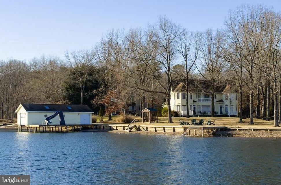 Welcome to 890 Tall Pines Drive, an exceptional waterfront retreat located in the sought-after Tall Pines Subdivision on the public side of Lake Anna, VA. Perfectly positioned on a level, prime point lot with 375 feet of bulkheaded shoreline, this turn-key lake home sits in a deep, no-wake cove, offering both breathtaking views and ideal lake conditions. Offered fully furnished, this property truly has it all—including the pontoon boat and three WaveRunners, all conveying for instant lake enjoyment. The expansive backyard is designed for entertaining and relaxation, featuring a firepit overlooking the water, a large enclosed boathouse with electric lift, a sundeck with a sliding board, and a separate fishing pier. Inside, you’ll find over 4,500 finished square feet with 6 bedrooms and 4.5 baths, all designed for comfort and hosting. Large windows frame stunning lake views, complemented by 9-foot ceilings, an open floor plan, and two gas fireplaces. The spacious kitchen flows seamlessly into the dining area and a separate breakfast room surrounded by windows, all overlooking the lake. This home features two primary ensuites—one on the main level and one on the upper level—along with standout amenities including an in-home sauna, movie room, and a converted garage turned ultimate game room complete with a pool table and more. The back deck, patio and covered balcony provide great spaces to relax with a book, coffee or cocktail in hand. A paved circular driveway and storage shed add convenience and functionality. Centrally located on the lake, this property offers easy access by boat to restaurants and marinas, and is just minutes by car to a local grocery store. Whether you’re seeking a primary residence, vacation home, or an investment to turn into a short term rental, this is truly the ultimate Lake Anna lake house in a prime location.