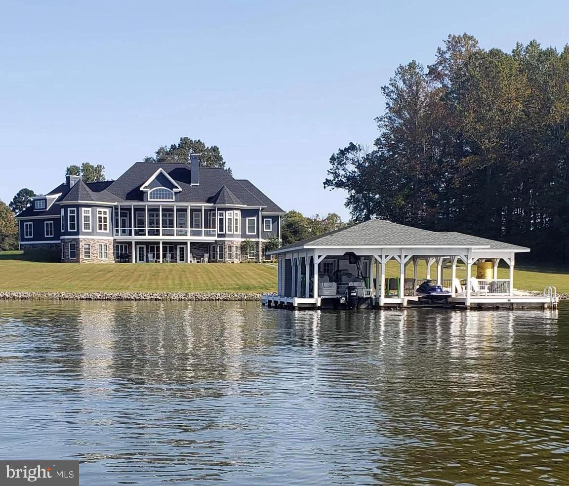 WOULD YOU LIKE TO PURCHASE THE PROPERTY AND INSTANTLY HAVE $200,000 OF INSTANT EQUITY. APPRAISAL JUST COMPLETED IN MARCH 2024 FOR $2,400,000. Your waterfront dream home awaits you.  Set upon the beautiful shores of Lake Anna, Virginia on the public side of the lake. This custom built retreat is nestled on 9.38 acres and has over 480+ feet of private shoreline, creating the ultimate lake oasis. This gorgeous retreat will bring your family together for gatherings for many years to come. Over 5,000+ square feet on two open levels, this paradise offers seamless indoor/outdoor lakeside living, with 5 bedrooms, 4.5 baths, an office, three stone wood burning fireplaces, a curved screened in back deck overlooking the water.  Step inside into a sunny open floor plan and gorgeous water views of Lake Anna's public side.  Gourmet kitchen supplies two islands, stainless appliances, granite counters and is open to the morning room and spacious family room.  Oversized primary bedroom suite is located on the main level as well, with a walk-in closet, tile shower and stand alone tub.  Walkout basement features a family room, rec room, 4 bedrooms, 3 full baths and a storage room.  A few steps away at the water, you’ll enjoy warm summer days down at your very own sandy beach and boathouse with two slips both with electric boat lifts, storage area, covered area, and a swim/sun deck.  Gather around the fire pit and roast s'mores after a day on the lake.  There is also a detached garage with an apartment on the property for rental income or guests!  The garage apartment has its own septic tank and has 3 bedrooms, 1 full bath, a living room and kitchen.  The lift and wood stove in garage can convey.  NO HOA and Short Term Rentals are Permitted! Furniture can also convey with purchase.  Great location, less than 2 hours from D.C and close to local dining, groceries and more.