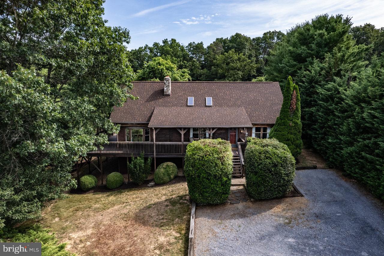 Country convenience! A cabin tucked away on almost 3 acres within 1 mile of Sentara RMH?  What a hidden gem! You'll know that you've found your new home as soon as you open the door into the great room. The floor-to-ceiling fireplace will catch your eye and warm your heart; nothing beats the cozy crackle of a real wood fire. The airy glow of natural light follows you into the kitchen/dining area, with windows inviting you out onto the wrap-around deck. Sights & sounds of nature surround you on the deck, whether you're embracing the sun's winter rays or seeking summer shade. A roomy primary suite, laundry, and pantry complete the main level. There's plenty of room for guests upstairs (or an office!) with 2 bedrooms, a full bath, and media area. Whether it's board games or a big screen, the finished basement rec room is your next fun hangout. Is woodworking your thing? Check out the workshop. Enough room for storage? The basement has you covered, and while you're there, check out the premium Gree 3-ton heat pump just installed in Oct 2023. The shed holds everything you need for the garden of your dreams in your massive back yard. R3 zoning offers additional intriguing investment possibilities- ask your agent for details. Call today!
