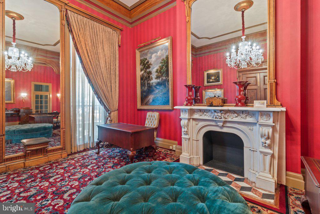 Previously used as a private physician’s office, Unit 14 occupies the parlor level and showcases 14-foot ceilings in the main rooms, with 11-foot ceilings in both the bath and a side room suited for a future kitchen. The space exudes a quiet grandeur, centered around an imported Italian marble mantel installed during a 1990s renovation that blended historic Mount Vernon character with refined European detail.

Sunlight streams through 11-foot east-facing windows overlooking Saint Paul Street, filling the rooms with warmth and highlighting the tall doorways, decorative trim, and elegant proportions. While no kitchenette is currently installed, the thoughtful layout includes a room that can easily be adapted into one—offering a seamless path from professional use to residential living.
The History: At the heart of Mount Vernon, 1118 and 1120 Saint Paul Street embody Baltimore’s architectural legacy. Designed and once occupied by George A. Frederick — the young prodigy behind Baltimore City Hall and the city’s park system — these brownstones reflect both history and craftsmanship. Now ,for sale within them are five distinct condominium units: dramatic parlor-level suites with soaring ceilings and ornate detail, alongside expansive lower-level spaces with flexible layouts and private entries. Together, they offer owner-users a rare mix of historic pedigree and practical adaptability in Baltimore’s cultural core.