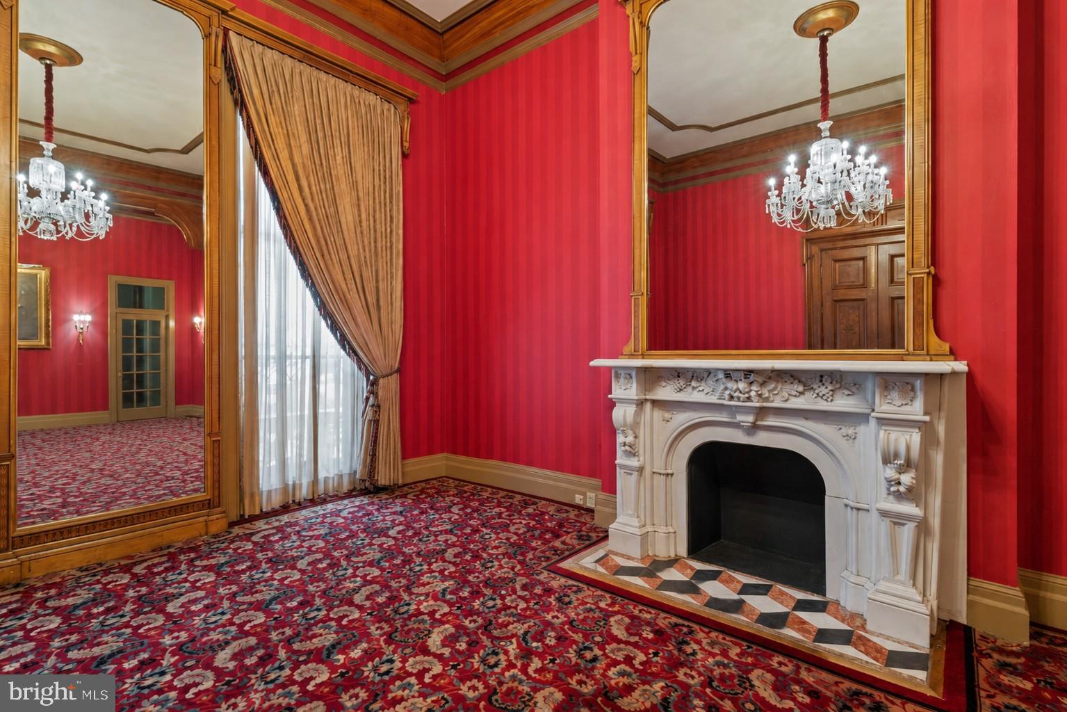 Previously used as a private physician’s office, Unit 14 occupies the parlor level and showcases 14-foot ceilings in the main rooms, with 11-foot ceilings in both the bath and a side room suited for a future kitchen. The space exudes a quiet grandeur, centered around an imported Italian marble mantel installed during a 1990s renovation that blended historic Mount Vernon character with refined European detail.

Sunlight streams through 11-foot east-facing windows overlooking Saint Paul Street, filling the rooms with warmth and highlighting the tall doorways, decorative trim, and elegant proportions. While no kitchenette is currently installed, the thoughtful layout includes a room that can easily be adapted into one—offering a seamless path from professional use to residential living.
The History: At the heart of Mount Vernon, 1118 and 1120 Saint Paul Street embody Baltimore’s architectural legacy. Designed and once occupied by George A. Frederick — the young prodigy behind Baltimore City Hall and the city’s park system — these brownstones reflect both history and craftsmanship. Now ,for sale within them are three distinct condominium units: dramatic parlor-level suites with soaring ceilings and ornate detail, alongside expansive lower-level spaces with flexible layouts and private entries. Together, they offer owner-users a rare mix of historic pedigree and practical adaptability in Baltimore’s cultural core.