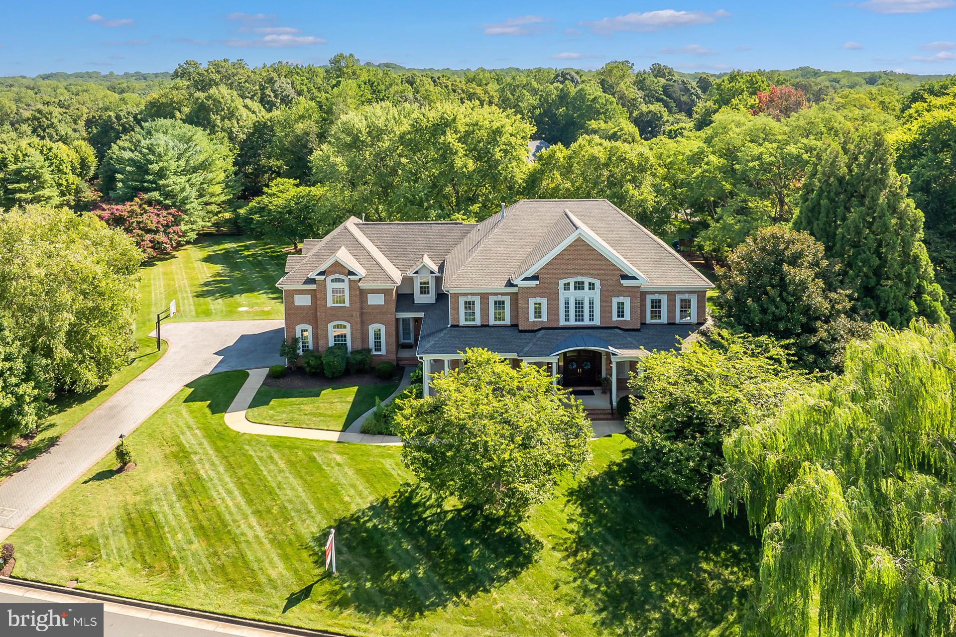 Your ideal home awaits! Discover unparalleled custom living—a perfect harmony of space, style, and practicality—with this remarkable Marquis Home, built by Van Metre. Nestled on a meticulously landscaped .99-acre lot in the beautiful Donovans Ridge community of Fairfax Station, this beautiful home offers over 8,000 square feet of sophisticated living space, including 5 bedrooms, 6.5 baths, a spacious bonus suite above the 3-car garage, and a finished lower level with a convenient kitchenette.
As you approach, a picturesque weeping willow and lush landscaping invite you in, while the pristine walkway, charming wrap-around porch, and stately front doors welcome you. Step inside to warm hardwood floors, and note the exquisite craftsmanship, from custom trim and molding to impressive transom and arched windows. The grand foyer with view of the two-story grand staircase, is flanked by the elegant formal dining and living rooms, making it ideal for hosting unforgettable gatherings. From the living room, you’ll find a convenient half bath, or you can head into the library/office with custom shelving—perfect for working from home.
The light-filled family room, featuring a wall of built-in shelves, deep cabinets and drawers, and a beautiful gas fireplace, connects effortlessly to the breakfast area and gourmet kitchen with an island. A perfect butler’s pantry and spacious walk-in pantry connects to the dining room, while a spacious mudroom, complete with a bathroom, leads into the garage. Enjoy outdoor living and entertaining on the screened porch, complete with a ceiling fan, or on the deck and the flat backyard—easily accessed from the family room, kitchen, mudroom, or lower level.
From the kitchen, take the back stairs, or from the family room, take the grand staircase to the upper level, where the floor plan is sure to impress. The luxurious primary suite is a retreat of its own, with a wall of windows, a private sitting area with a balcony, and two walk-in closets.  The spa-like bath with a separate tub and shower features a new double vanity with cultured marble counter. Two additional bedrooms share a full bath, while a fourth bedroom has its own hall bath. Each bedroom has a walk-in closet providing plenty of storage space.  Three built-in bookshelves in the hallway complement the cozy loft with a window seat providing a perfect reading nook adjacent to the impressive laundry room. An exciting feature of this charming home is the suite over the garage offers two walk-in closets, a bedroom, a living area with custom desk system, full bath, and dedicated HVAC; ideal for an au pair, in-laws or a home business. 
The spacious walk-up lower level rec room, complete with a kitchenette and full bath, is the perfect location for hosting movie or game night! Also on this level, you’ll find a flexible bonus room with windows for hobbies or exercise equipment, and plenty of extra storage space. **See the detailed special features & Updates pages, floor plans, and a 3D walkthrough**  Fantastic community amenities abound just minutes away, including major shopping, restaurants, recreational and cultural opportunities. Nearby go fishing, canoeing or camping at Burke Lake Park and Golf Course, attend classes at GMU or NVCC, see wonderful art at The Workhouse in Lorton, meet friends at Paradise Springs Winery, or head to the area’s charming historic towns like Occoquan and Clifton. Schools/Universities: Fairview Elementary, Robinson Secondary, and George Mason University. The community is a commuter's dream—just moments from Fairfax County Parkway, Burke VRE, Springfield Metro, and airports.  Don’t miss this opportunity to make this exceptional home yours—schedule a showing today and experience the lifestyle that awaits!
