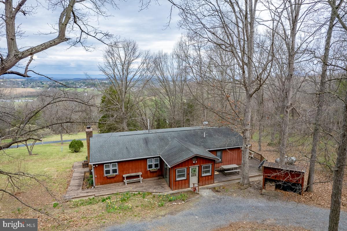 Privacy, mountain views, and nearly 10 acres — this spacious ranch checks every box. The open, single-level layout includes 3 bedrooms, 2 bathrooms, a dedicated office, and not one but two living rooms, both with custom built-in bookshelves. The family room with a wood stove— because some evenings just call for a real fire, opens up to a beautiful screened-in porch with those awesome views. The oversized owner's suite comes with an attached sitting room that's ready to become your reading nook, home gym, or that hobby room you've been promising yourself. A 2-car garage with workshop space, open shed, and circular driveway round out the package — and with 9.9 acres right outside your door, hikers and gardeners, disc golfers and bikers, and more are going to feel very much at home.