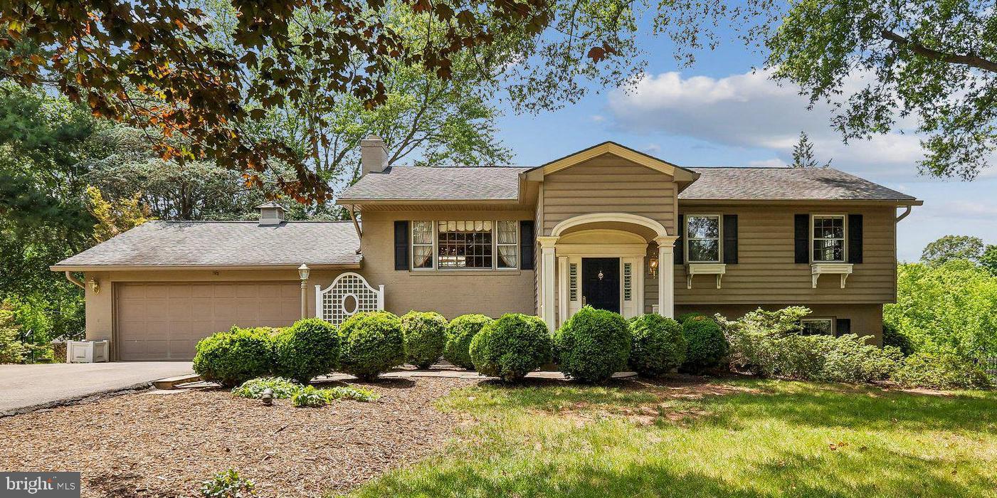 Offered for sale for the very first time since its construction in 1974, this 2,582 sq.ft. residence has been lovingly cared for, thoughtfully expanded, and proudly owned by the same family for more than five decades. Nestled on 1.55 acres in rural Prince William County and zoned Agricultural, this rare offering combines enduring craftsmanship, remarkable privacy, and a peaceful country setting with the convenience of nearby amenities. Best of all, there is NO HOA.

From the moment you arrive, the property's attractive curb appeal is evident. A split-rail fence frames the front of the property, while a removable access point allows convenient entry to the entire parcel—perfect for trailers, work vehicles, recreational equipment, or future projects. The expansive grounds provide abundant off-street parking and a sense of seclusion seldom found in today's market.

Step inside and be greeted by a classic open foyer; a custom addition designed by the owners to create a spacious ‘welcome’ for family and guests alike. Rich hardwood flooring extends throughout the entry, staircase, hallway, living room, dining room, and bonus room, setting the tone for the home's timeless character. The interior is far larger than it appears from the street, offering an abundance of space designed for both comfortable daily living and memorable entertaining.

The traditional living room flows naturally into the dining room, creating elegant gathering spaces ideal for holidays and special occasions. Just beyond, the bright and airy kitchen features Italian marble flooring and serves as the heart of the home, connecting seamlessly to both the dining room and the spectacular bonus room addition.

Designed and constructed by the original owners, the bonus room showcases a vaulted ceiling and sweeping views of the rear grounds. Bathed in natural light, this inviting space opens directly to a private outdoor dining area, creating a wonderful indoor-outdoor lifestyle. The family room offers warmth and character with its raised-hearth Italian marble fireplace featuring gas logs, while atrium doors lead to a covered stone patio tucked within the landscape; again, perfect for entertaining, or simply relaxing. 

The owner's retreat was created by combining two original bedrooms into one impressive sanctuary that contains ample room for sleeping, sitting, and dressing.  Features include an en-suite bath, two generous closets, and atrium doors opening onto a sun-drenched private balcony.  This desirable layout offers a wonderful opportunity to update and re-imagine the space while personalizing the decor to your liking.

Outdoor living is equally captivating. The elevated entertaining deck wraps from the bonus room to the owner's balcony, creating multiple spaces to relax, dine, and enjoy the surrounding scenery. Beyond, manicured grounds unfold with perennial flower gardens, mature plantings, and open lawn areas that provide a tranquil backdrop throughout the seasons. A meandering stream gently winds through the backyard, enhancing the property's natural beauty and oasis-like atmosphere.

Additional features include two substantial storage sheds nestled among the gardens, a heated workshop with its own 200-gallon propane tank, an attached two-car garage, and parking for four additional vehicles. Practicality meets preparedness with a 17-kilowatt whole-house generator powered by a 1,500-gallon propane tank. The propane system also supplements the home's heating, working in conjunction with the whole-house wood stove to provide dependable comfort year-round.
Properties of this caliber rarely become available. Combining quality construction, generous living areas, picturesque outdoor spaces, and the distinction of being offered for sale for the first time ever, this one-of-a-kind residence presents an extraordinary opportunity to create your next chapter. Schedule your private showing today and experience everything this remarkable property has to offer.