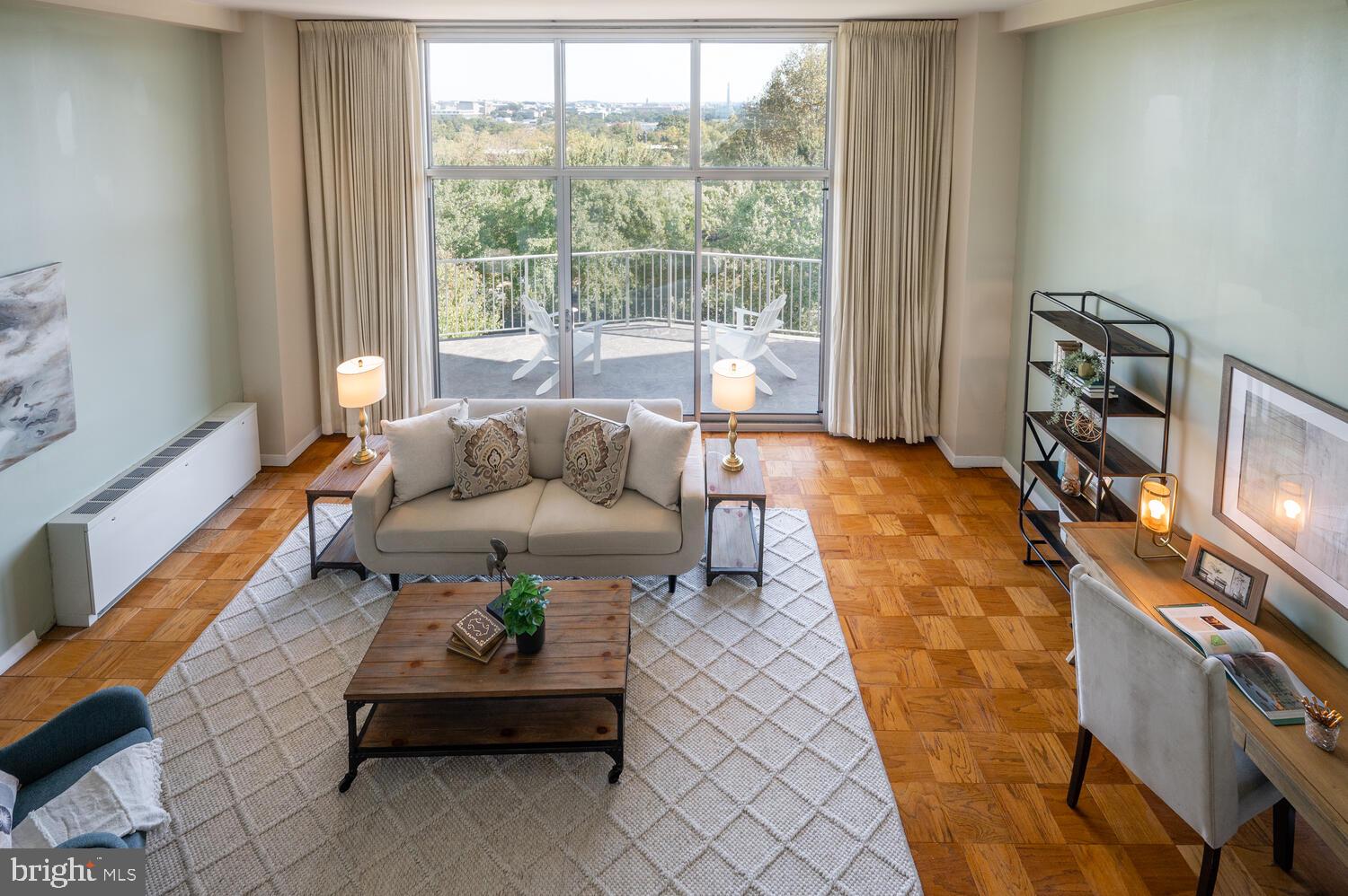 Renovated mid-century modern condo in the heart of Rosslyn with stunning monument/city views and two indoor parking spaces. The Prospect House, designed by architect Donald Hudson Drayer, is featured in James Goode’s seminal book on DC’s “Best Addresses” and offers ground-breaking modernist design with captivating views of Washington and prime, convenient location. The 2 bed/2 bath 1,398-square-foot airy and light-filled space features dramatic living room with 13-foot ceilings and full wall of glass looking out to the expansive private balcony and those monument views. The Prospect House is not your standard vanilla condo. From the folded-plate porte-cochère to the preserved mid-century lobby, the building would feel at home in Los Angeles or Palm Springs. One of the unique designs of the building is that the units are open on both sides (east and west exposure) to let air and light flow through.
The design of the unit places the entrance on the 5th floor with an entranceway and sizable closet. Steps then drop down to reveal the soaring living room and view out the wall of glass and huge walls to display your modern art. The living room and dining room have original parquet floors and the renovated kitchen and bathrooms are clad in ceramic tile. The high-end open kitchen features extensive storage and stainless-steel appliances. The renovated hall bathroom has a soaking tub while the primary ensuite bathroom has a glass-enclosed shower clad with ceramic and glass tile and sitting bench. In addition to the renovated bathrooms and kitchen, all the glass and HVAC convectors have been updated.  
The monthly condo fee covers all utilities, heated outdoor pool, exercise room and 24-hour reception/security, storage as well as trash, snow removal, landscaping and all exterior maintenance, among other items. The on-site convenience store and cleaners add to the easy lifestyle.
Perched on a hill on a direct axis with the National Mall and just above the Iwo Jima Memorial and Netherlands Carillion, the Prospect House is just minutes to the Rosslyn Metro, the shopping and restaurants in Clarendon, National Airport, Georgetown, Rock Creek Park and Foggy Bottom.