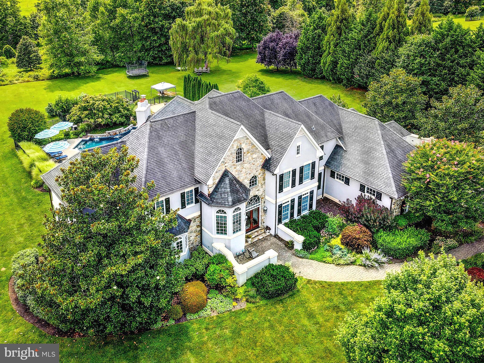 Situated within the desirable neighborhood of Cloverland, this gorgeous French country style home welcomes you as a place of respite and serenity.  Winner of the Home Builders Association "Home of the Year",  sitting on just under 7 acres and backing to 50 acres of preserved land, enjoy all that nature has to offer with a stream running along the edge of the property, mature fruit trees sprouting with figs, cherries, and more, and raised garden beds with bountiful harvests.  This retreat boasts 6 bedrooms, 4 full and 2 half bathrooms, center two-story foyer, custom millwork, two fireplaces, formal study with coffered ceilings and built-in bookshelves, and a mudroom with custom lockers, just to begin.  On the upper level, the impressive primary suite is complete with a gas fireplace, sitting room, dual walk-in closets, back entrance, and tranquil ensuite.  Separate vanities, soaking tub, water closet, walk-in shower with rainfall shower head and a thoughtful glass window opening to heated towel racks for great convenience, await in the ensuite.  Remainder of the upper level consists of two separate wings, each with two bedrooms and a full bathroom.  Furthest bedroom currently serves as a quaint library, just next to the laundry room.  You’ll find the heart of the home in your spacious kitchen, overflowing with natural light, oversized island with seating, walk-in pantry, beverage fridge, prep sink, sitting area, as well as a breakfast nook which overlooks both your living room fireplace and your resort style yard.  Step out onto your rear deck and down the steps to relax in your spa tub, soaking in views of the in-ground heated pool, its fountains, pool house, and greenery providing the utmost privacy.  Acreage stretches beyond a wooden playground to a field that would allow for an additional outbuilding or make a perfect grazing pasture, just awaiting a horse or two.  Should you need space for an au pair or in-law suite, they would find their own private entrance on the rear of the home through French doors into the walkout lower level.  This space includes a sun-filled bedroom (with additional rough-in next-door for a potential 5th full bath) and kitchenette, just down the hall from a full bathroom.  Movie buffs alike will appreciate the home theater area with a motorized projector, built-in speakers, and starlight ceiling.  This beautiful, multifunctional open floor plan design was featured in Houzz home design and is perfectly integrated with the whole house Crestron automation system.  Additional amenities include home gym, ample storage space, three-car garage with GarageTek storage system, widened parking area on driveway, copper gutter system, and partial generator.  Impeccable abode just waiting to impress in person.