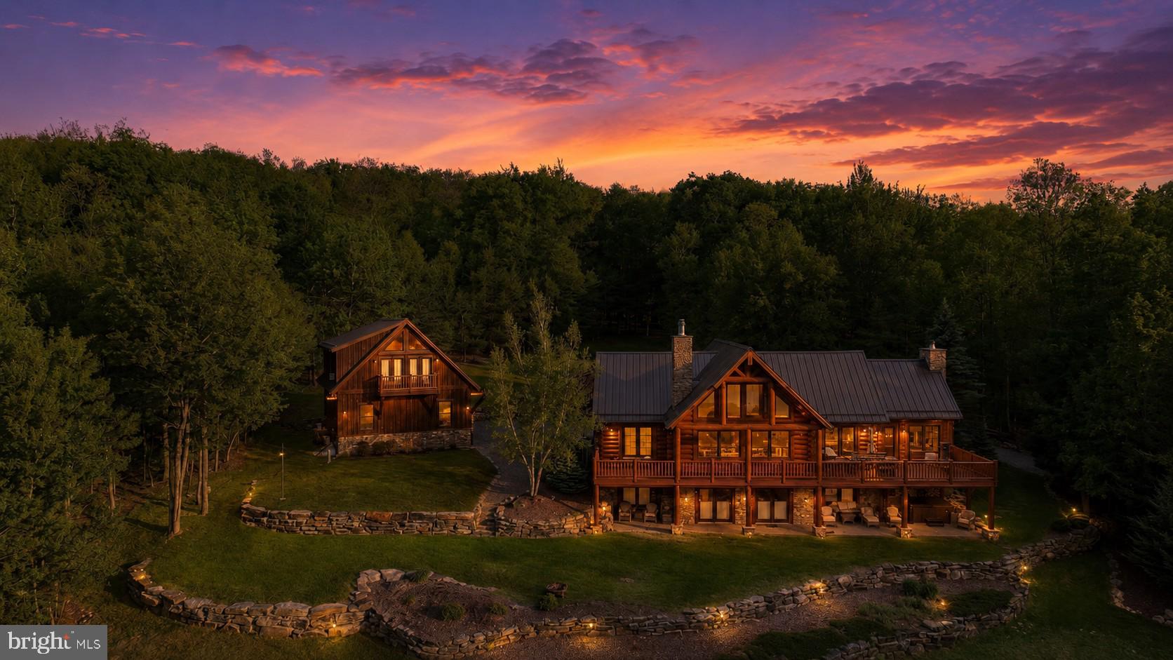 Experience what may be the most spectacular view in all of Deep Creek Lake! Perched in an extraordinary setting, this exceptional Yellowstone Log Home showcases breathtaking panoramic water views that create a true “top of the world” feel. Designed to capture the scenery from every angle, the main level features an open-concept layout with soaring natural light, a stunning stone fireplace, luxury kitchen, spacious primary suite, and a beautiful three-season room with its own stone fireplace. Step outside to the expansive deck—perfect for entertaining, relaxing, and taking in unforgettable sunsets. The loft offers flexible living space ideal for an office, rec room, or additional lounge area. Downstairs, the finished lower level includes a second family room with stone fireplace, an additional primary suite, two more bedrooms, full bath, and walk-out access to a covered patio. The impressive 40’ x 28’ detached garage provides three bays of storage plus finished living space above with a bedroom suite, living area, bunks, and private deck overlooking the lake. A rare opportunity to own one of Deep Creek Lake’s most unforgettable vantage points—where luxury, space, and unmatched scenery come together.