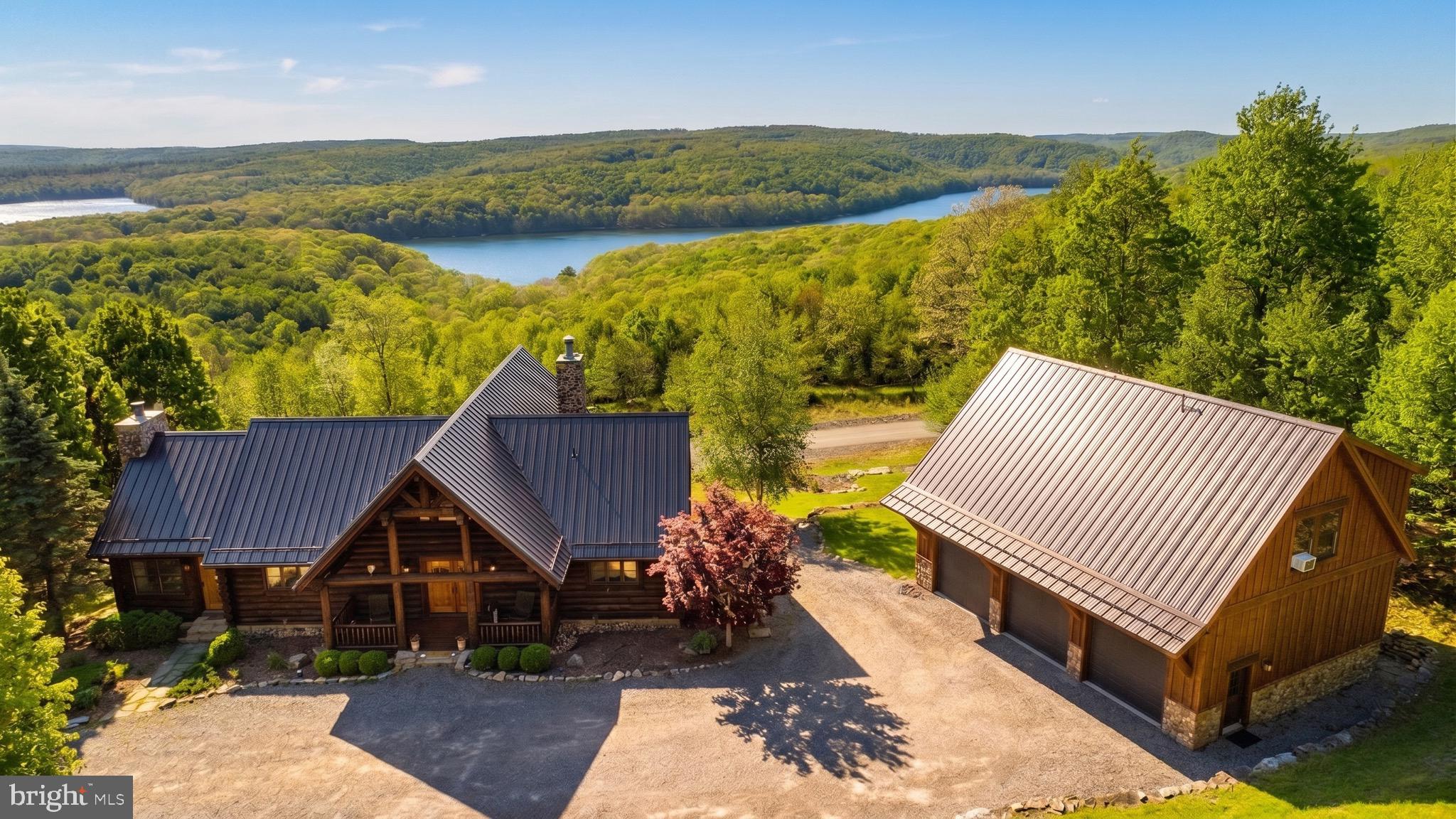 Experience what may be the most spectacular view in all of Deep Creek Lake! Perched in an extraordinary setting, this exceptional Yellowstone Log Home showcases breathtaking panoramic water views that create a true “top of the world” feel. Designed to capture the scenery from every angle, the main level features an open-concept layout with soaring natural light, a stunning stone fireplace, luxury kitchen, spacious primary suite, and a beautiful three-season room with its own stone fireplace. Step outside to the expansive deck—perfect for entertaining, relaxing, and taking in unforgettable sunsets. The loft offers flexible living space ideal for an office, rec room, or additional lounge area. Downstairs, the finished lower level includes a second family room with stone fireplace, an additional primary suite, two more bedrooms, full bath, and walk-out access to a covered patio. The impressive 40’ x 28’ detached garage provides three bays of storage plus finished living space above with a bedroom suite, living area, bunks, and private deck overlooking the lake. A rare opportunity to own one of Deep Creek Lake’s most unforgettable vantage points—where luxury, space, and unmatched scenery come together.