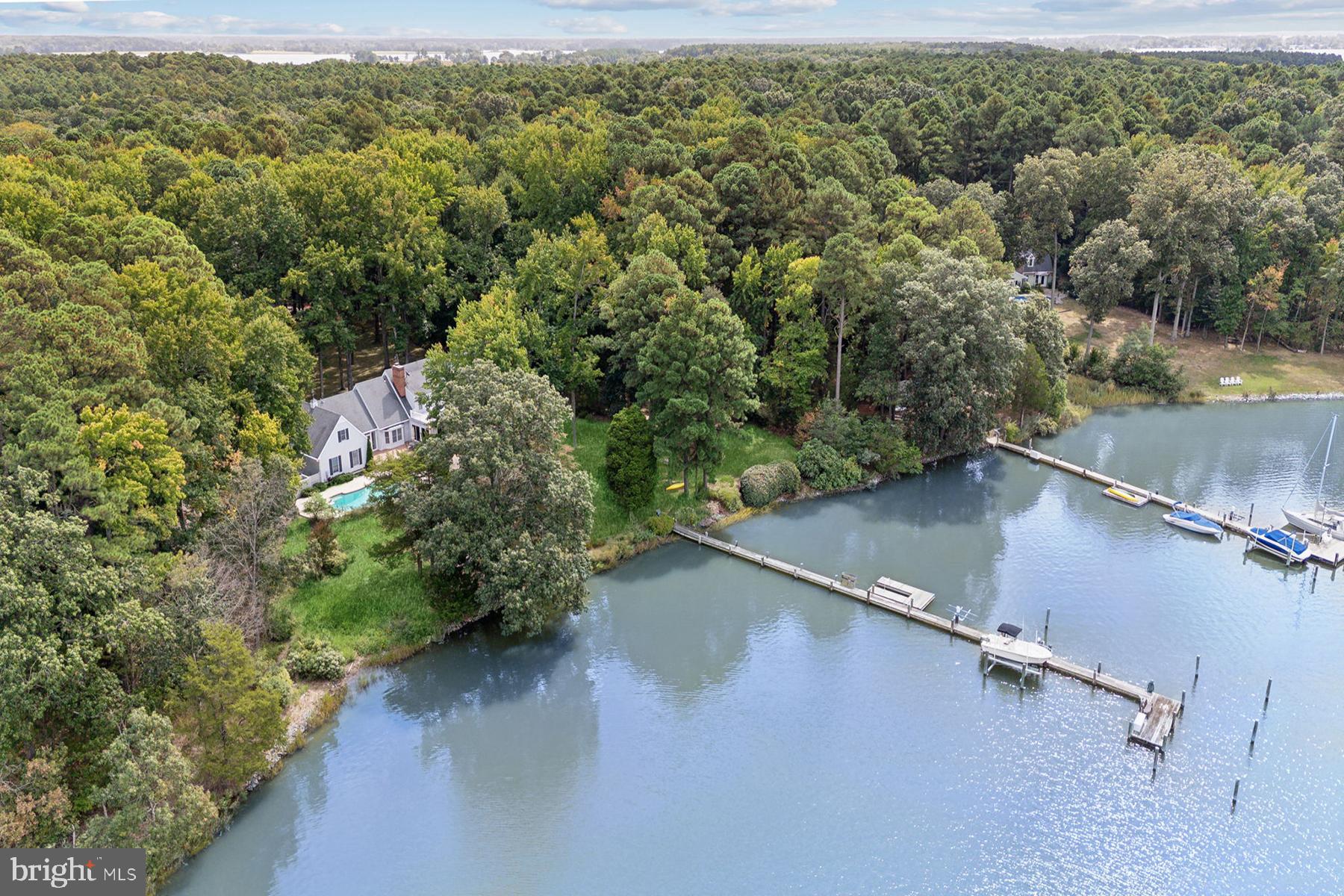 Location, Westerly Views, Sailboat Depth Water, Privacy! Welcome to this stunning waterfront home, a true sanctuary overlooking Plaindealing Creek. Spanning 4074 square feet, this residence includes 4 spacious bedrooms, 3 full baths, and 2 half baths, providing ample space and comfort for family and guests. Sited on 5.06 acres of beautifully manicured grounds and stunning mature trees, the property has 327' +/- of natural shoreline and 6-7' MLW, ideal for boating enthusiasts. The private pier features two boat lifts, three deep-water slips, and a large floating dock. Enjoy breathtaking 180-degree views of the water from much of the house, or from the in-ground heated saltwater pool. Inside, you will find beautiful hardwood flooring throughout and an abundance of natural light.  The living room and sunroom showcase big views of the pool, back yard, and creek from multiple sliding glass doors leading to an expansive wrap-around waterside deck. The large family room w/ cathedral ceiling has French doors to the deck, and a wonderful wood-burning fireplace. The main level primary bedroom with ensuite bath and large walk-in cedar closet are private and overlook the back yard and creek. Adjacent is the separate office with great built-ins and desk. The light-filled eat-in kitchen with center island is convenient to the formal dining room, a pantry/mudroom area, and wonderful breezeway with brick flooring serving as a screened porch/additional sunroom. On the second level, enjoy three well-appointed guest bedrooms, a full hall bath, and a second access point to the walk-in attic space over the garage. The home's thoughtful design includes extensive storage space & cedar closets, an enormous walk-in attic,  bonus area accessed by a spiral staircase, and a dedicated fitness room complete with an adjacent steam shower/steam room. An attached 2-car garage with access to the walk-in attic overhead, workshop, and wonderful built-ins, and storage shed complete the property.