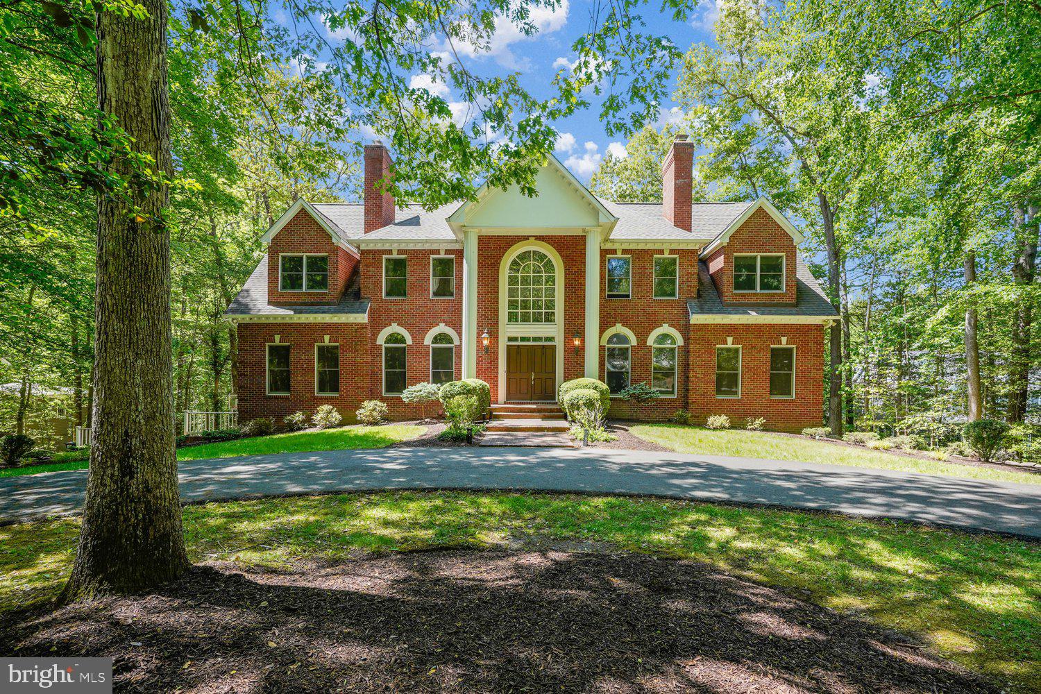 This timeless, all-brick colonial sits on 1.72 private acres with a welcoming elegant semi-circular drive. Spanning 6,500 square feet across three finished levels, the home features an open-concept layout with 9-foot ceilings and expansive windows that flood the home with natural light.
The main level is designed for modern living, boasting of hardwood floors throughout the dining area, family room, and the gourmet kitchen. The kitchen is equipped with granite countertops, a center island with a hood, a gas cooktop, and a Sub-Zero refrigerator. This floor also includes a private office and a highly coveted FIRST FLOOR BEDROOM  AND a full bath.
Upstairs, the grand owner’s suite serves as a true retreat. The primary bedroom showcases a tray ceiling, a cozy fireplace-lit sitting room, spacious walk-in closets, and three additional bedrooms.  The lower level is a bright, walk-out lower level that is a home unto itself.  Featuring a full kitchen, two full bathrooms, two additional rooms, and a laundry room with two washers and dryers. Outside, the property is a haven for relaxation and entertaining, offering a large deck that overlooks the expansive backyard and a patio centered around a fire pit. Additionally the home has a sprinkler system, a generator, Air purifier, Water softener, Central vacuum, built in gas grill and Tesla charger installed.