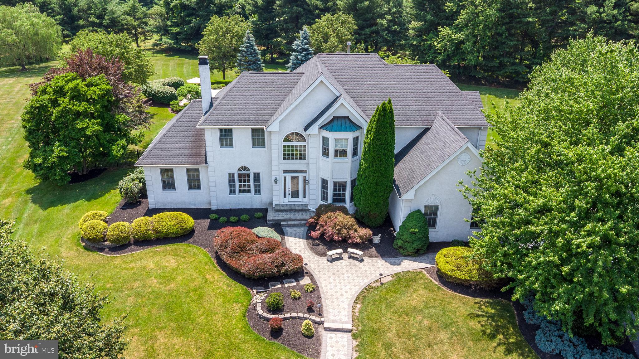 Perfectly maintained and thoughtfully updated, this exceptional Richboro home offers elegant living spaces and an extraordinary backyard retreat on 1.5 professionally landscaped acres in the award-winning Council Rock School District,  just minutes from parks, shopping, restaurants, and major highways. A paver front patio and walkway lead to the dramatic two-story foyer, where French doors open to an office with custom built-ins. The formal living room shares a marble two-sided gas fireplace with the light-filled sunroom, creating two inviting spaces for relaxing or entertaining. The formal dining room with its vaulted ceilings and hand-painted frescos is perfect for hosting special occasions. The thoughtfully remodeled kitchen (2016) is truly the heart of the home, featuring granite countertops, abundant cabinetry, a tumbled marble backsplash, a pantry, and a spacious eating area. The kitchen opens to the inviting family room with soaring 20-foot ceilings, a custom built-in bar, and a wall of windows overlooking the backyard. A laundry room, powder room, and oversized three-car side-entry garage with an electric vehicle charging station complete the main level. Upstairs, the primary suite features two walk-in closets, a comfortable sitting area, and a luxurious renovated bath (2022) with radiant heated marble floors, quartzite countertops with double sinks, a jetted tub, and a double walk-in shower. Three additional well-sized bedrooms, a hall bath, and a balcony overlooking the dining room,  complete this second level. The finished basement, designed with extra ceiling height, offers an impressive amount of additional living space, including an expansive recreation room, a huge mirrored fitness room, a charming playhouse tucked beneath the stairs, and plenty of storage space. Step outside and discover your own backyard oasis. A spacious paver patio spans the entire rear of the home and overlooks the newly renovated 38,000-gallon in-ground pool with heated spa (2026).  The pool is surrounded by expansive flagstone decking. The fully equipped pool house opens completely with a motorized door, creating an indoor-outdoor entertaining space with an island, refrigerator, sink, TV, and full bathroom. Beyond the pool and the beautifully landscaped grounds, is an expansive lawn for sports and play, all within the privacy of the fenced backyard. Additional improvements include a new roof (2019), hot water heater (2021), Generac whole-house generator (2023) and three-zone heating and air conditioning, reflecting the meticulous care evident throughout this gorgeous home.