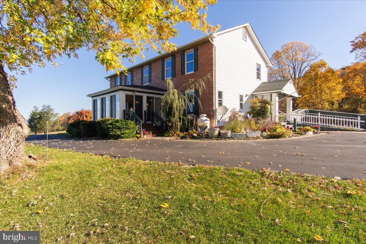 Rural setting on 21 Acres in Jefferson Md. in Frederick County with exceptional 30-mile panoramic views. Absolutely breathtaking! This home is perched on the side of the mountain with a combination of open land and woods. This attractive home features 3 finished levels totaling over 3,600 sq. ft. You will love the open first floor plan that features laminate flooring, painted & stained wood ceilings, an expansive kitchen, a glass-enclosed front sunroom capturing the scenic views, a comfortable family room, spacious dining room and a glass enclosed rear porch.  The walls of the main staircase feature shiplap siding, herringbone design stair railing, stained wood treads with painted risers, stained glass artwork at the top of the stairs with an attractive hanging light. Upstairs boasts 4 bedrooms and 2 bathrooms with generous bedroom sizes. This home has plenty of windows and is light and bright throughout.  The basement level is finished with a huge recreation room, an exercise room and finished open space. Note the 8' tall old church doors installed from an old church in Brunswick. This lower level walks-out on grade. There is also a separate building classified as an "addition" and is connected to the house with a 95' breezeway. The additional building was permitted through Frederick County 25+ years ago, is on a separate septic system but shares the same well as the main house.  It was approved for a living room, den, sewing room, 2 bedrooms and 3 bathrooms. It is not presently approved to have a kitchen and is not allowed to be used as an apartment-type building. This “addition” structure is 1800 sq. ft. plus a finished basement (disclosures to be provided for approved and potential uses). Enjoy the walking trails through the woods. There is also a spring fed pond.  Overall, this property has so much to offer.