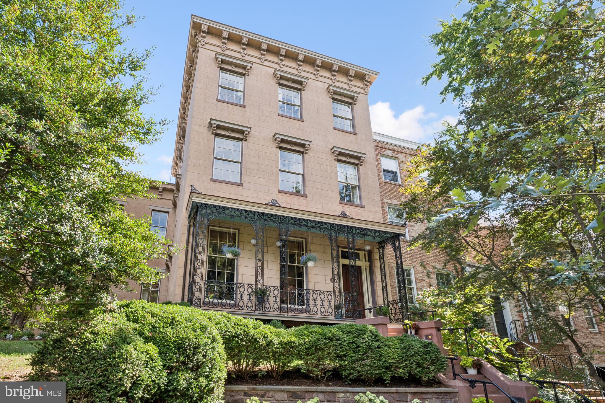 The Alexander Graham Bell House | Step into a Gilded Age fantasy with this extraordinary Greek Revival corner residence, built in 1854 and once home to Alexander Graham Bell and his family. Steeped in history and architectural splendor, this six-bedroom, six full and two half-bath Georgetown estate is a masterwork of 19th-century elegance, meticulously preserved and thoughtfully updated.

A Grand Historic Interior

Spanning four gracious levels, the home is centered around a sweeping mahogany staircase rising beneath a stained-glass skylight. Echoes of Upstairs/Downstairs living abound—from working call bells connecting principal rooms to the kitchen, to grapevine and acanthus-leaf moldings, faux bois doors, paneled window shutters, and intricate brass hardware.

The twin parlors—perfect for formal entertaining—feature marble fireplaces with carved acorn details, gilded crown moldings and chandelier medallions. Stained-glass pocket doors lead into the formal dining room, where striped wood floors extend into a ballroom-like space framed by Palladian triple-hung windows that open to the terrace garden and fountain. Period chandeliers, cut-crystal sconces, and etched glass fixtures complete the unified decorative scheme.  The main level half-bath features an antique Edward Johns & Co sink, period high-tank commode, and opaline glass light fixtures.

Chef’s Kitchen & Terraced Garden

The light-filled, eat-in kitchen blends historic charm with modern functionality. Anchored by a wood-burning fireplace, it includes Wolf and Sub-Zero appliances, a mix of butcher block and stone counters, and fully functional original call bells. French doors open directly to the lush, walled terrace garden—an urban sanctuary complete with mature plantings and a stone fountain.

Private Quarters & Lavish Suites

The original second-floor primary bedroom is bathed in natural light and adjoins a marble-and-tile ensuite bath with Waterworks fixtures and a towel warmer. A nearby study/library features a marble fireplace and access to a canopied terrace, as well as a concealed Eastlake-style wet bar outfitted with a copper sink, pomegranate-motif painted tiles, and herringbone cabinetry.

A later addition brings a private octagonal primary suite enhanced with opaline glass tiebacks, floral plaster medallion, and dual bathrooms. One features a marble sink, tile shower, and Waterworks fittings; the other offers a large marble vanity within a spacious dressing room, complete with a built-in ironing station and Jacuzzi tub.

On the third floor, two additional bedrooms each offer marble fireplaces, custom built-ins, and full ensuite baths with clawfoot tubs, pedestal sinks, and antique light fixtures.

Lower Level

Accessible via private staircases, the fully equipped lower level includes a two-bedroom in-law or rental suite with twin closets, a full and half bath, and a dedicated laundry. Period elements abound: original tile floors, a Dutch door, cast-iron hardware, and tongue-and-groove detailing. The historic butler’s pantry and second laundry station add charm and functionality.

Additional Features Include:

Oversized two-car garage with ample storage and recent improvements

Copper flashing and drainage throughout

Original enamel doorknobs, locks, and fixtures throughout

Multiple fireplaces, including wood-burning and decorative marble

Thoughtful updates with Waterworks, Lefroy Brooks, and Czech & Speake fixtures

A Rare Opportunity

Located within the Georgetown Historic District and listed on the D.C. Inventory of Historic Sites, the Alexander Melville Bell House represents an extraordinary convergence of heritage, craftsmanship, and luxury. It is not merely a home—it is a legacy, ready for its next steward.