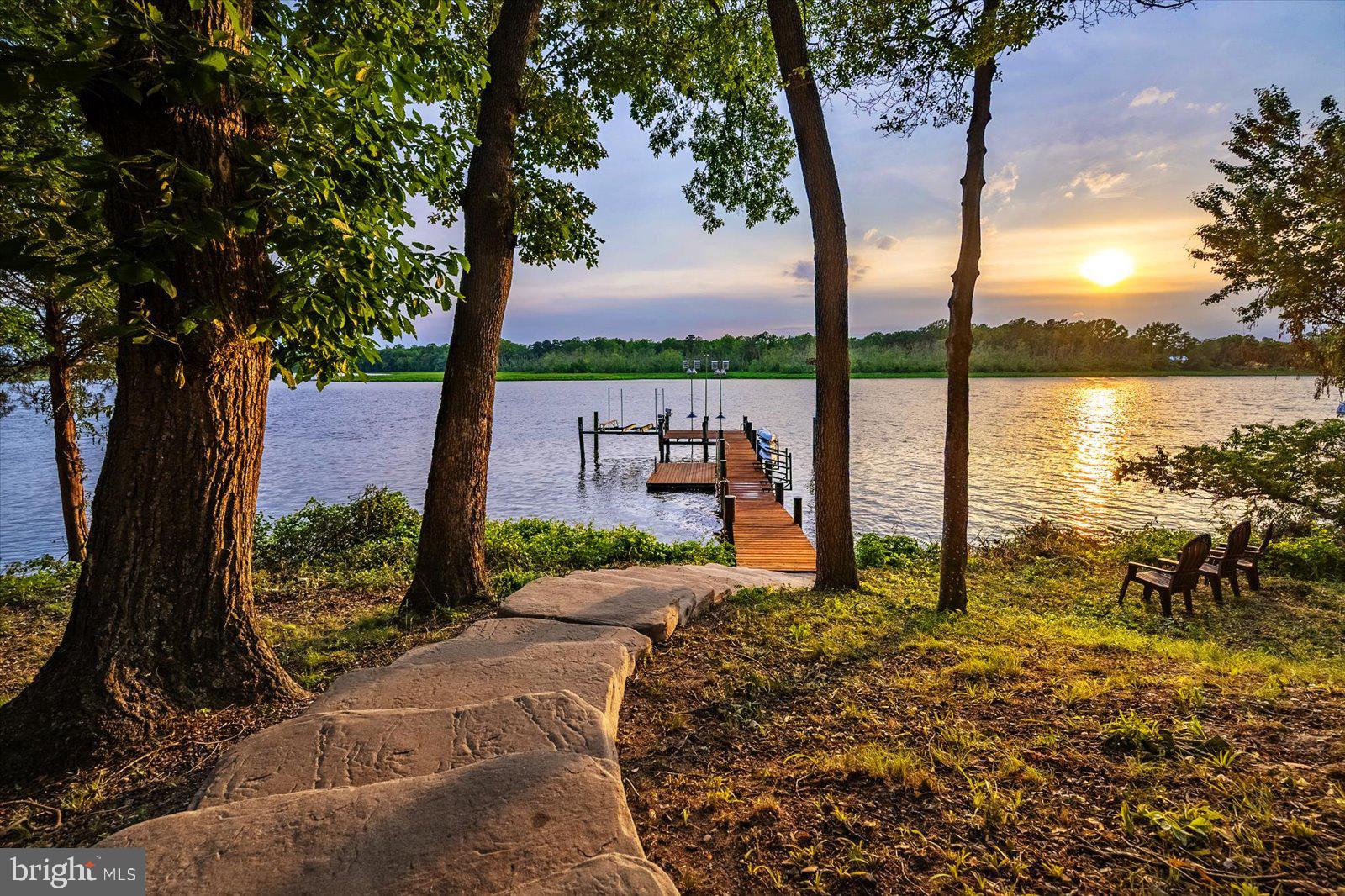 Wake up to sunrise on the Choptank River and wind down with some of the most stunning sunsets on the Eastern Shore — with Ospreys, Eagles, Herons, and an abundance of wildlife as your daily backdrop. This stunning 4,853 sq ft waterfront estate sits on 2.44 acres with 268 feet of private river frontage, putting you right on the water and just steps from the best of historic downtown Denton. Built in 2006 and extensively renovated in 2016, this 5-bed, 4.5-bath home has been meticulously maintained — nothing to do but move in. 
Two private primary suites on the main level each offer a serene river view retreat, ideal for multi-generational living or hosting guests in style. Three additional bedrooms upstairs provide room to spread out. Soaring 9-ft ceilings, hardwood floors with a dark walnut finish, maple paneling, and a custom Hagerstown Kitchens kitchen set the tone for quality throughout. Entertain on the brand-new Trex deck (2025) or unwind on the screened porch with spectacular western sunsets — and those views are yours forever. The land across the river is a protected Resource Conservation Area.
All major systems are in excellent condition and maintained on yearly service contracts: three Carrier variable-speed HVAC units, dual Rinnai tankless water heaters, closed-cell foam insulation, and Hardie Board siding.
The private dock features 8 ft MLW, a boat lift, and dedicated kayak dock with water, 240V power, and security cameras — accessed via hand-laid stone steps. Ospreys, Eagles, Herons, and Owls are regular visitors.
A dedicated wellness room with river view includes a voice-command sauna, cold plunge, full shower, and workout space. The 3-bay epoxy-floored garage with LED lighting offers abundant storage for all your gear.
A short walk to historic downtown Denton — an Eastern Shore best-kept secret with Eden Town Brewery, award-winning Caroline's Restaurant, Clayton Farms, and Shore Gourmet and the Chesapeake Culinary Center. Easton, St. Michaels, and Oxford are less than 30 minutes away, while Annapolis, Ocean City, Rehoboth Beach, Assateague, and Chincoteague are all within roughly an hour. You're already in the heart of it all.