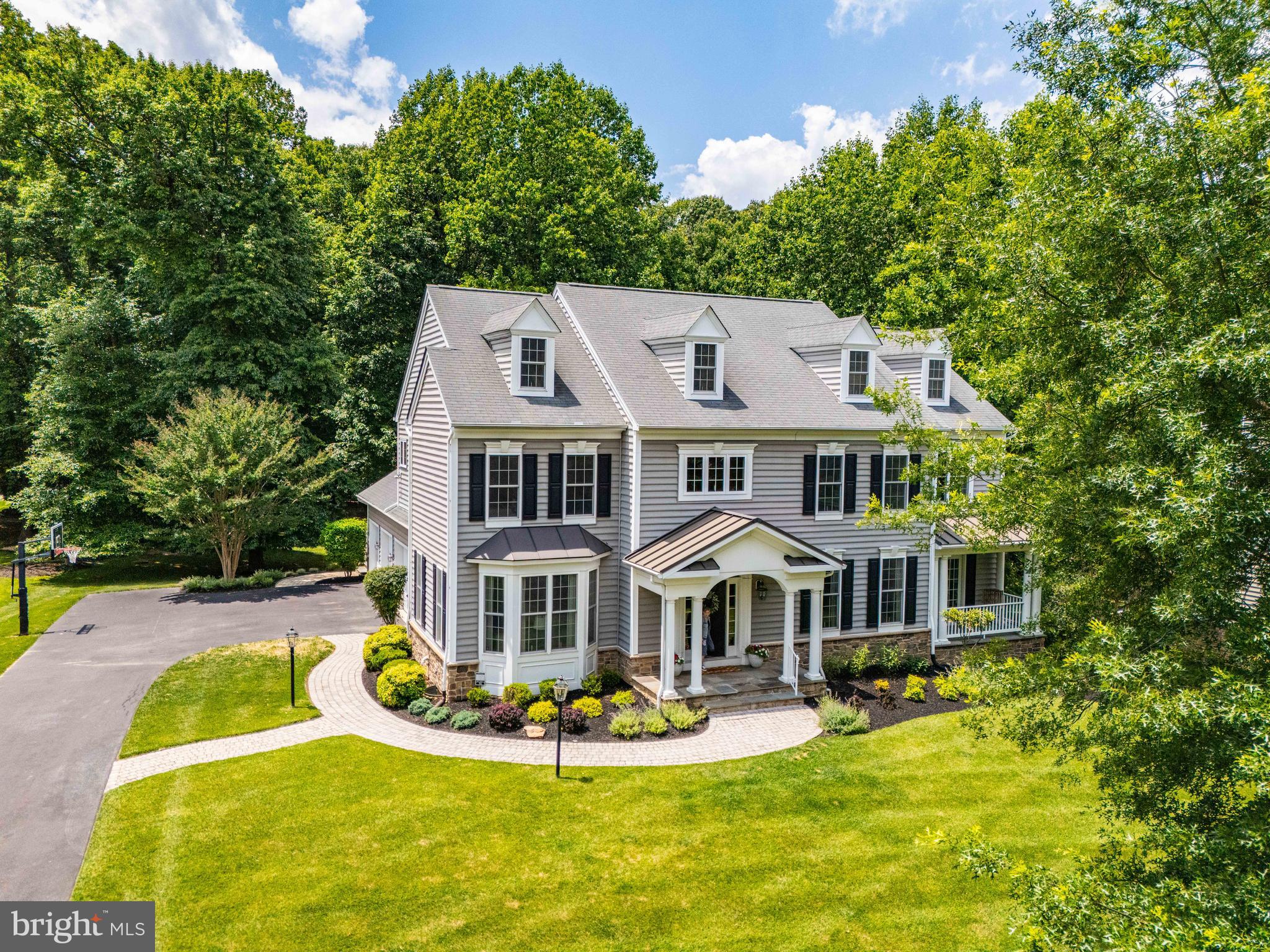 Welcome to 4325 Buckskin Wood Drive, an extraordinary Georgian residence on a private wooded acre in highly sought-after Lakeview at Buckskin Ridge. The striking stone-and-siding façade, oversized side-load 3-car garage, and triple covered porches make a strong first impression.
 
Inside, a grand foyer welcomes guests with a sweeping curved staircase and hardwood floors flowing into spacious formal living and dining rooms, a butler's pantry with display cabinetry, and a private home office with French doors leading to its own covered porch. A powder room and mud/laundry room with direct access to the covered side porch and garage add everyday functionality to the main level.
 
At the heart of the home is a newly completed chef's kitchen showcasing full-height KraftMaid Vantage cabinetry, quartz countertops with a built-in John Boos prep station, 30" fireclay farm sink, and premium Thermador and Alexa-enabled Signature Kitchen Suite appliances. The centerpiece is a 9'x5' island topped with a John Boos 2¼" rock maple commercial bakery butcher block, offering seating for three and abundant storage below. The pantry and 11' two-seat workstation/buffet complete the kitchen, while 8-foot French doors open to a large screened outdoor living room and composite deck overlooking the private wooded backyard.
 
The kitchen flows seamlessly into the great room, which features soaring 18-foot ceilings, abundant natural light, a fieldstone gas fireplace, and 5.1 surround sound wiring. A striking secondary staircase with overlook creates an impressive architectural focal point.
 
Upstairs, the spacious primary retreat offers a large walk-in closet and private bath with dual vanities, soaking tub, separate shower, and private water closet. A Jack-and-Jill bath connects two generously sized bedrooms, while a fourth en-suite bedroom is ideal for guests. Oversized hall and linen closets provide additional storage.
 
The expansive walk-out lower level with a full-bath rough-in and new active radon mitigation system offers exceptional potential for future finished living space, along with ample storage and a workshop area with 240V subpanel service. Just outside, an integrated storage shed adds convenience without compromising the home's aesthetic.
 
Smart home features include CAT6 wiring, Alexa-enabled LED lighting, and dual Ecobee thermostats. Additional upgrades include a Russound 4-zone whole-home audio system, Culligan water softener, and whole-home water filtration.
 
Combining craftsmanship, thoughtful updates, and a private wooded setting, this outstanding home offers the best of western Howard County living — just minutes from Columbia/Clarksville, schools, and major commuter routes.  A rare opportunity in one of the area's most sought-after communities.