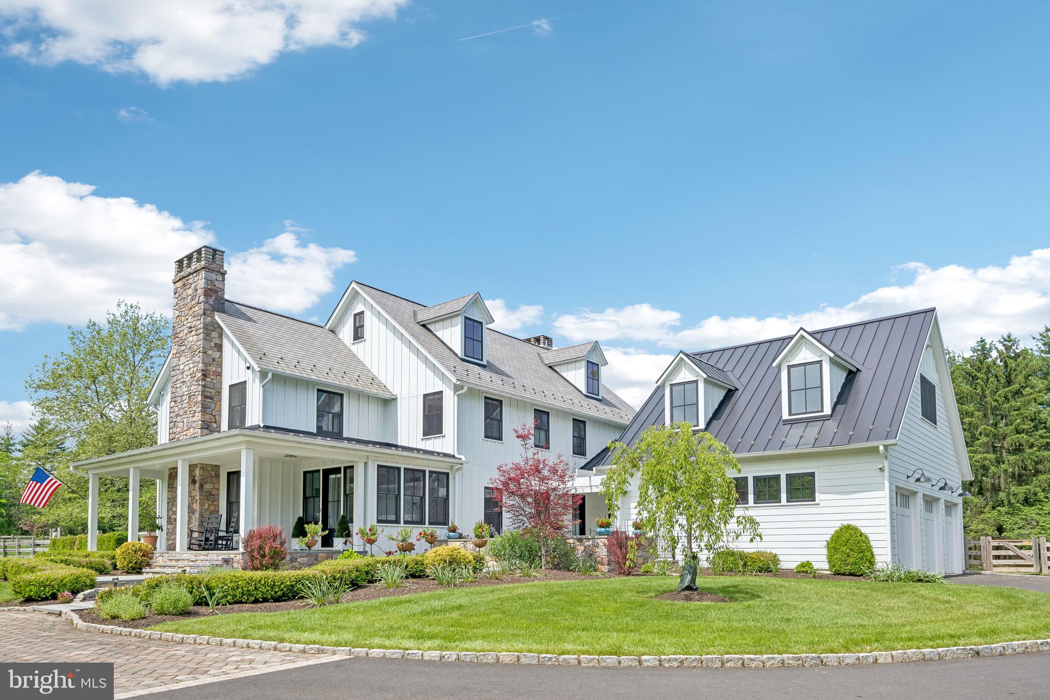 Originally crafted by Worthington Homes and magnificently reimagined for today’s luxury lifestyle, this extraordinary modern farmhouse colonial is gracefully set on 3 pristine acres within Upper Makefield’s  Windy Hollow community. Offering 4 bedrooms, 4 full & 2 half baths, the completely remodeled residence showcases a seamless blend of timeless architecture, sophisticated design & uncompromising quality. From the moment you arrive, the home makes a striking impression. Newly installed Hardie Board siding, new roof, all new windows & doors, along with a newly added bluestone front porch, courtyard & walkway, create a stately yet welcoming presence, while the beautifully manicured grounds enhance the property’s estate-like setting. Step inside the redesigned entrance addition where warmth, elegance & craftsmanship immediately unfold. Rich hardwood flooring spans all three levels, complemented by recessed lighting, custom window treatments & refined architectural details throughout. The formal living room offers an intimate gathering space with a fireplace & custom moldings, while the elegant dining room is adorned with crown molding, wainscoting, built-in cabinets & direct courtyard access for effortless indoor-outdoor entertaining. Nearby, the richly appointed study features custom built-ins & detailed millwork. A beautifully renovated powder room completes this wing of the home. At the heart of the home is the spectacular great room highlighted by a coffered ceiling, fireplace & wet bar with beverage refrigerator—ideal for both grand entertaining & relaxed everyday living. The reimagined state-of-the-art chef’s kitchen is simply stunning with custom white cabinetry, designer gold hardware, exotic stone countertops & a dramatic double-thickness center island. Luxury appointments include pendant lighting, a custom wood hood, pot filler, wine & beverage refrigeration & professional-grade stainless appliances including a built-in refrigerator, double ovens with steam, drawer microwave, range-top with 4 gas burners, 2-zone induction, sous vide & dishwasher. Adjacent is an exceptional pantry room lined with extensive cabinetry & an additional renovated powder room. A private staircase leads to a separate suite complete with an updated full bath—ideal for guests, au pair, extended family—while access to the immaculate 3-car garage with epoxy flooring, storage, EV charger, utility sink & bike lift is conveniently nearby. Upstairs, two secondary bedrooms each enjoy beautifully updated en-suite baths. The thoughtfully designed laundry room features custom cabinetry, quartz countertops, oversized sink, tile flooring & washer and dryer elevated on pedestals. The magnificent primary suite serves as a luxurious private retreat with fireplace & custom beverage center. An extraordinary dressing closet includes extensive built-ins & a center chest with stone countertop. The spa-inspired primary bath features dual oversized vanities, extensive storage, an oversized curb-less shower with dual shower heads & body sprays, soaking tub, heated floors & private water closet. The added third-floor space offers a versatile lounge area plus substantial unfinished space already suited for expansion into two additional bedrooms & another full bath. The finished lower level provides exceptional recreation space highlighted by a temperature-controlled 246-bottle wine cellar. Outside, a wraparound deck overlooks the fenced rear yard framed by mature professional landscaping. New paver walkways connect the home’s outdoor spaces, while a whole-house generator & two new HVAC systems provide peace of mind. A large storage building with shed dormer adds both character & functionality. Every inch of this exceptional residence has been thoughtfully renovated with the finest finishes & craftsmanship. Ideally located near major highways, trains, parks, shopping & everyday conveniences, all within the award-winning Council Rock North School District