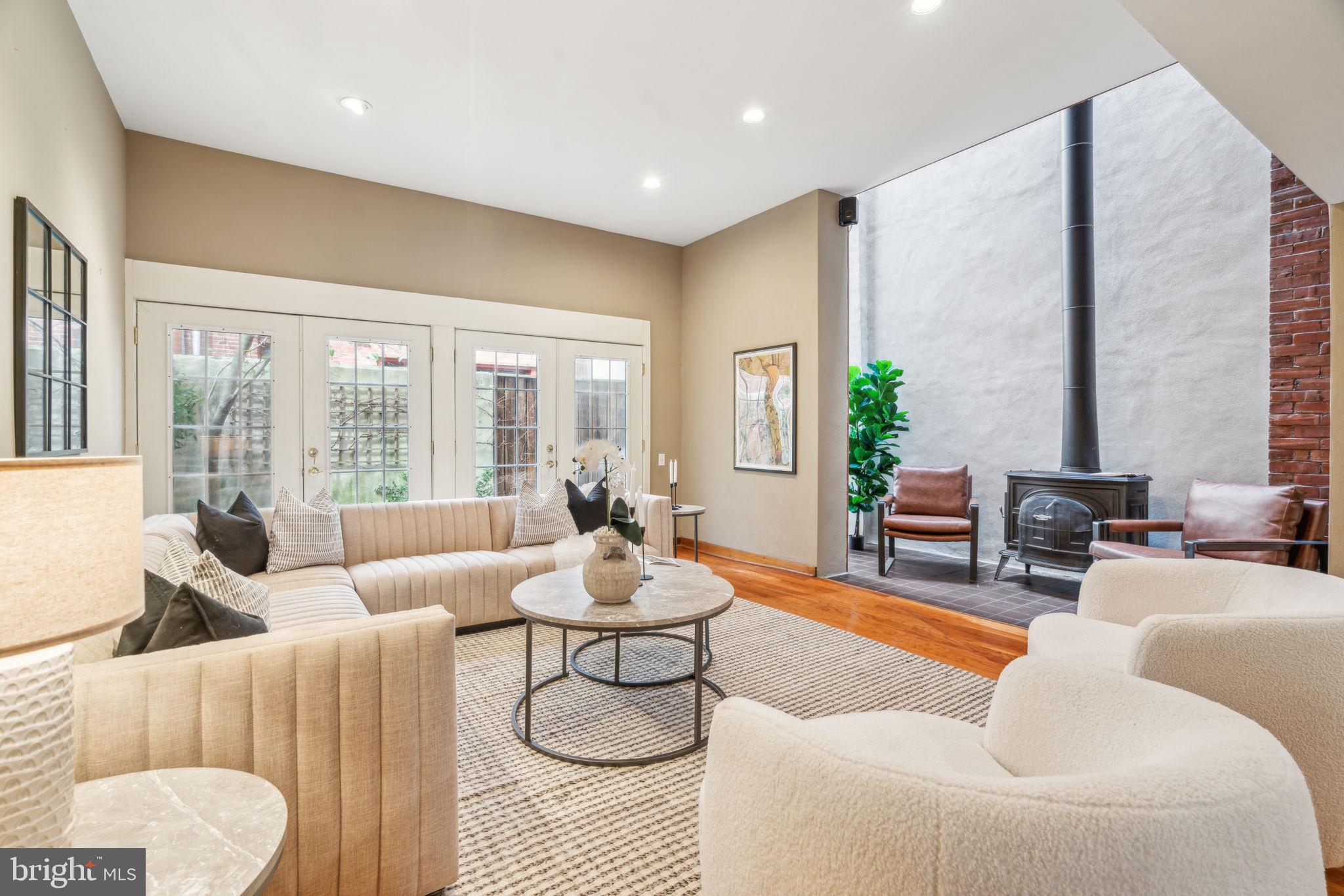 Contemporary design meets historic architectural provenance in this stunning three-bedroom, two-bathroom Cecil Baker-designed townhouse featuring sun-splashed interiors, abundant storage, private outdoor space, and garage parking on the sought after “Golden Mile” in vibrant Queen Village.

Rarely available in this prime location, this 2,194-square-foot stunner is filled with tall ceilings that rise above gleaming hardwood floors, handsome wood millwork and built-ins. A gracious foyer welcomes you into the first floor’s open-plan living space. Enjoy casual dining or game nights alongside a wall of shelving, or curl up with a good book in the striking double-height light well featuring glass brick and a warm wood-burning stove. In the expansive living room, two sets of oversized French doors open the space to the charming, walled rear garden for seamless indoor-outdoor living.

On the second floor, an inviting formal dining room is ideally located next to an open kitchen featuring rows of cabinetry and stainless steel appliances. A powder room and a family room flanked by floor-to-ceiling shelving and the home’s iconic projected bay window make this level ideal for entertaining and relaxing.

On the top floor, the owner’s suite beckons with a king-size bedroom, generous closet space, and an en suite bathroom with a walk-in shower. Two spacious and bright secondary bedrooms offer custom woodwork and exposed brick details, arched windows, roomy closets, and access to a full hall bathroom with a large tub/shower. Central HVAC, a sprawling basement with a laundry area, and a garage add comfort and convenience to this special Philadelphia townhome.

Ideally located where Bella Vista meets Queen Village, this exceptional residence enjoys outstanding walking, biking, and transit scores and fantastic proximity to some of the city’s best shopping, dining, and nightlife. On the surrounding blocks, you’ll find the beloved Italian Market, parks and playgrounds, and a fantastic array of international cuisine. Whole Foods and Center City amenities are minutes away, and transportation is a breeze thanks to excellent bus service, the expressway, and SEPTA and PATCO trains all nearby.