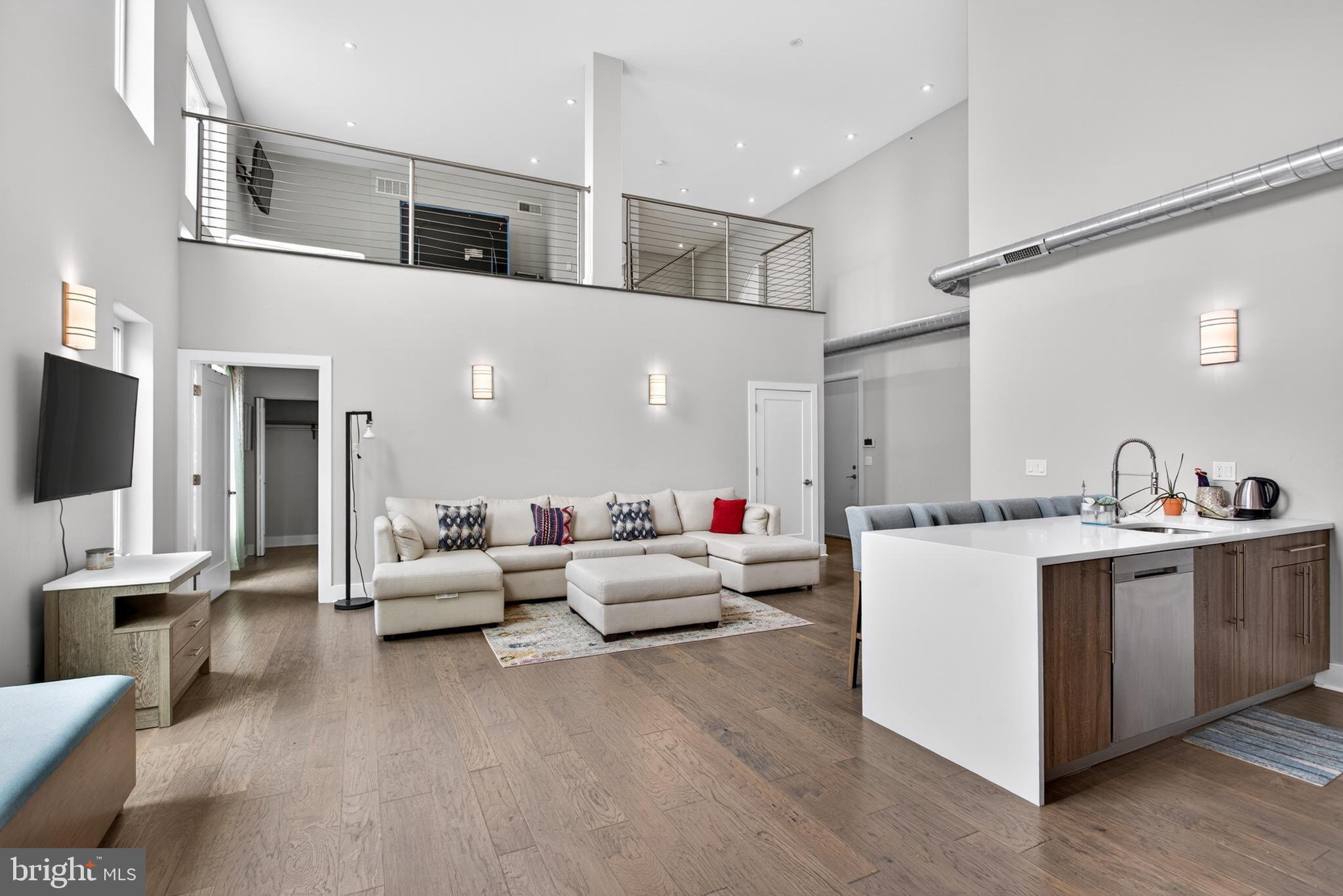 Welcome to 1526 Ridge Avenue, Unit #4, a stunning 2-bedroom, 2-bathroom home with a loft in Philadelphia's vibrant Fairmount neighborhood. Blending modern finishes with dramatic architectural details, this home offers soaring ceilings, abundant natural light, and flexible living spaces designed for today's lifestyle. As you enter, a welcoming hallway leads you into the impressive main living area, where 20-foot ceilings and luxury vinyl plank flooring create an open and airy atmosphere throughout. The living room is highlighted by dramatic stacked windows that flood the space with natural light, creating a bright and inviting setting for relaxing or entertaining. Overlooking the living area, the kitchen features an island with seating, stainless steel appliances, and a convenient pantry closet, offering both style and functionality. Adjacent to the kitchen, the dining area includes a built-in bench seat and direct access to the private deck, providing the perfect spot for morning coffee or outdoor dining. A full hall bathroom features tile flooring, a single sink vanity, and a tub/shower combination with an upgraded luxury shower head. Just beyond, the second bedroom offers bright windows and a ceiling fan with light, making it an ideal space for guests, a home office, or additional living needs. Located off the entry hallway, the spacious primary suite serves as a private retreat with the same dramatic 20-foot ceilings, large windows, and a generous walk-in closet. The en-suite bathroom features tile flooring, a double sink vanity, illuminated vanity mirrors, and a step-in shower with a luxury shower head. Above the second bedroom, the versatile loft area offers additional living space complete with windows, a modern railing system, and a closet. Whether used as a home office, reading nook, fitness area, or lounge space, this bonus area adds exceptional flexibility to the home. Not only does this home have everything you need, but it also places you in the heart of Fairmount, just steps from local restaurants, cafes, shopping, entertainment, public transportation, and everything this sought-after Philadelphia neighborhood has to offer. Don't miss the opportunity to make 1526 Ridge Avenue, Unit #4 your new home.