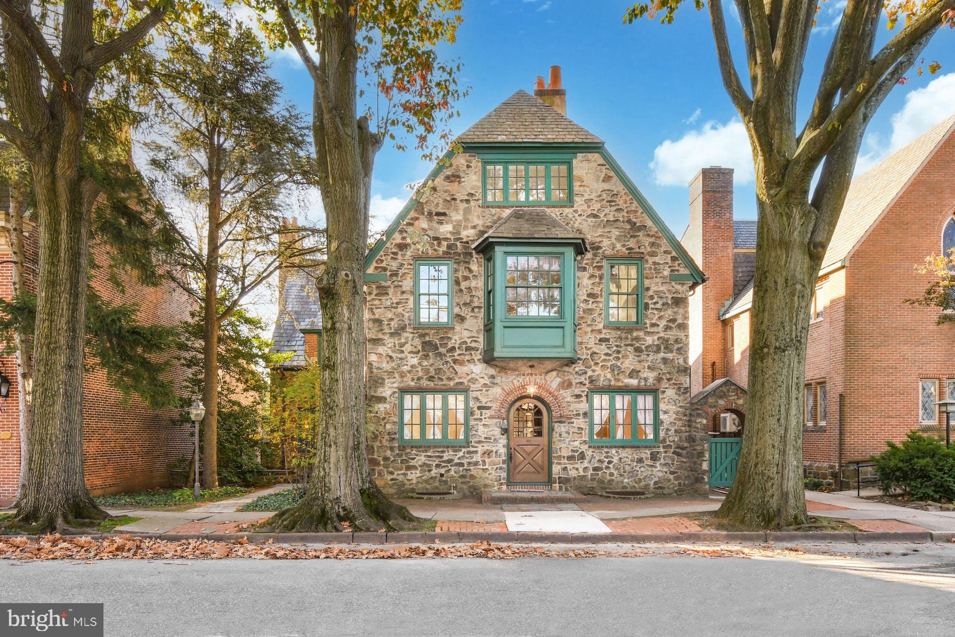 One of Historic Bethlehem’s most admired stone homes, East Market Street was built in the 1920’s as a doctor’s residence. The stone walls of the house are striking, and there are stunning architectural details with brick appointments, arches with solid oak doorways, slate roofs with intriguing rooflines, all reminiscent of an English country home, with stone walled patios and original leaded and stained-glass windows.
Much care has been taken with the restoration and enhancement of this beautiful and historic residence. There is a floor plan of 6928 finished square feet on four floors, with five bedrooms and a lower level walkout apartment … unique enhancements for an Historic Bethlehem residence. To create a modern functioning floor plan, walls were removed to open space for the magazine ready 2021 kitchen renovation costing $235,000 and boasting quartz waterfall counters and every high-end appliance imaginable. The new blends seamlessly into the adjoining rooms with period details such as magnificent woodwork, moldings, built ins and balconies. Throughout the home are original chandeliers, sconces, hardware, and custom designed nooks and crannies. Of special interest are the three fireplaces with Moravian tile, brick and concrete surrounds. The living room boasts 10-foot ceilings, mullioned glass French doors and leaded glass window bay. The primary bedroom has 10-foot ceilings, a fireplace and a bath with a lovely 2017 remodel of marble and glass.
Continuing outside, there is a lovely garden area with paver walkways, circular patio and specimen plantings. Parking for more than six cars, as well as an attached garage, are very rare for homes in the area. This home is a treasured addition to the Bethlehem Historic District and one that welcomes you to all the benefits and joy of walking to dinner, Moravian Academy and friends.