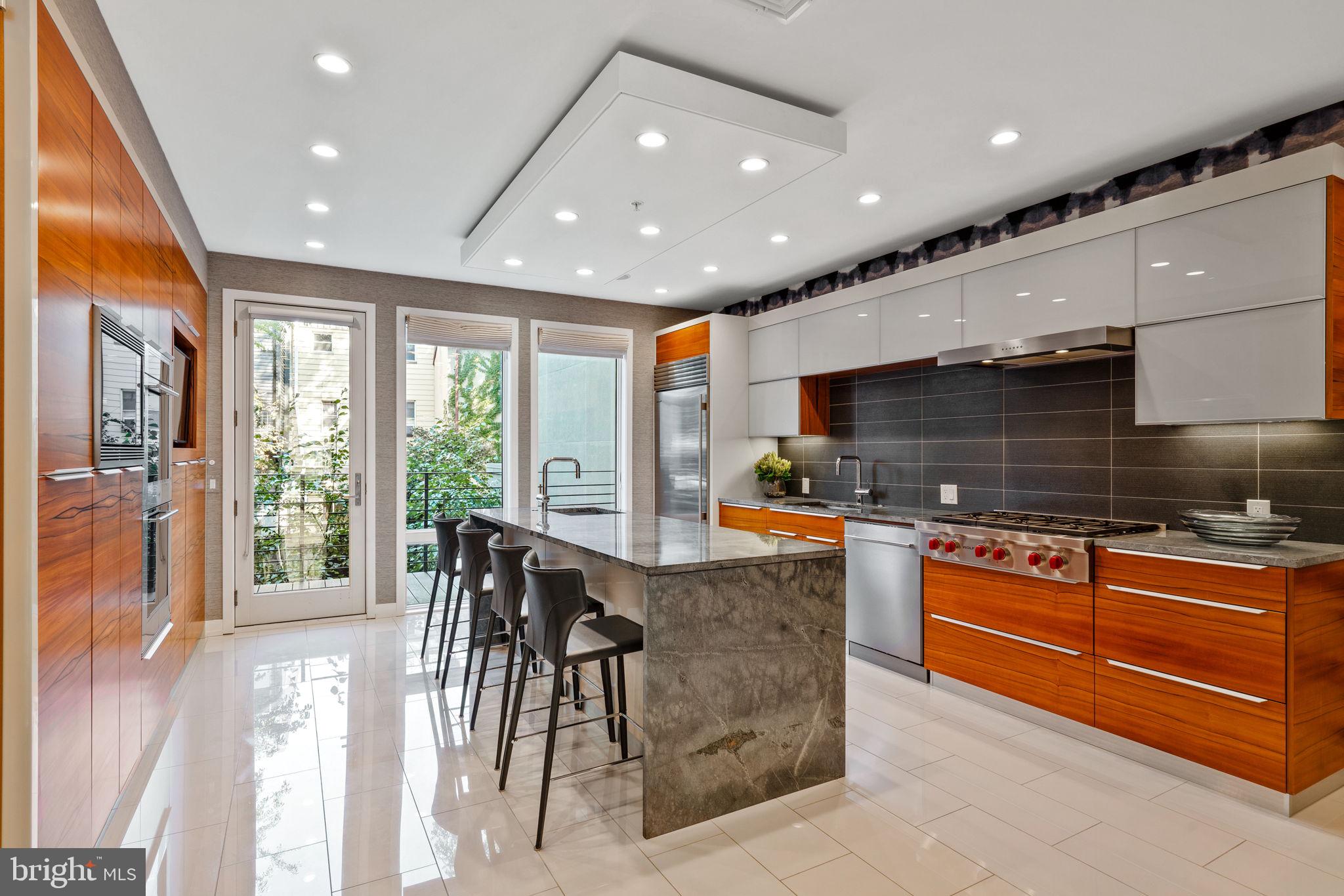 Impeccable modern luxury awaits in this sublime three-bedroom contemporary townhouse featuring breathtaking designer interiors and several levels of remarkable private outdoor space. Remaining tax abatement is the cherry on top of this not-to-be-missed showplace, located where Bella Vista meets Queen Village. Custom-built in 2018 and finished by a renowned interior designer, this nearly 4,000-square-foot residence impresses with a sleek, upscale ambiance, premium finishes, and every modern convenience you'd expect. On the ground floor, the dramatic foyer introduces custom paneling, designer wallcoverings, and beautiful hardwood and marble tile floors that create an elevated aesthetic. A large game room with a wet bar and access to the rear patio nods to the seamless indoor-outdoor entertaining spaces you'll find throughout the magazine-worthy home. Continue downstairs to the large home gym and access to the hydraulic car lift. The second floor sets the stage for grand gatherings with a sunny living room flanked by chic built-ins, a fireplace, a wall of windows, and a second powder room. Plan your next dinner party under designer lighting in the stunning dining area positioned alongside the jaw-dropping open kitchen. This world-class cookery pairs custom cabinetry and gray stone countertops with a fleet of upscale appliances, including a Wolf cooktop, Sub-Zero refrigerator, Meile wall ovens, and more. Wine lovers, take note! The wall of custom wine refrigerators accommodates up to 500 bottles of your precious collection, while the adjacent deck delivers the perfect destination for sharing your favorite vintage with friends. The home's luxurious accommodations begin on the third level, where the full-floor owner's retreat is filled with custom closets, cabinetry, and a dressing area vanity. The king-size bedroom invites you to gaze over treetop views while the massive sun-splashed spa bathroom wows with a freestanding soaking tub, walk-in rain shower, double vanity, and private water closet. On the floor above, stylish wallcoverings create a glamorous home office while two sophisticated secondary suites with private baths face front and back. This extraordinary home's crowning glory is the sprawling roof deck that spans the entire footprint of the property. With a hot tub, a summer kitchen, outdoor television, and integrated speakers, this outdoor oasis is perfect for game day gatherings, evening stargazing, and extravagant al fresco dining surrounded by the city skyline. An attached garage with a car lift installed maximizes off-street parking while the industrial-chic façade adds outstanding curb appeal to this Platinum LEED-designated home on a peaceful, low-traffic block. This exceptional Philadelphia neighborhood boasts outstanding walking, biking, and transit scores thanks to its central location filled with some of the city's best shopping, dining, and nightlife. On the surrounding blocks, you'll find the beloved Italian Market, charming parks, and a fantastic array of international cuisine. Center City amenities and cultural destinations are minutes away, and transportation is a breeze thanks to excellent bus service, the expressway, and SEPTA and PATCO trains all nearby.