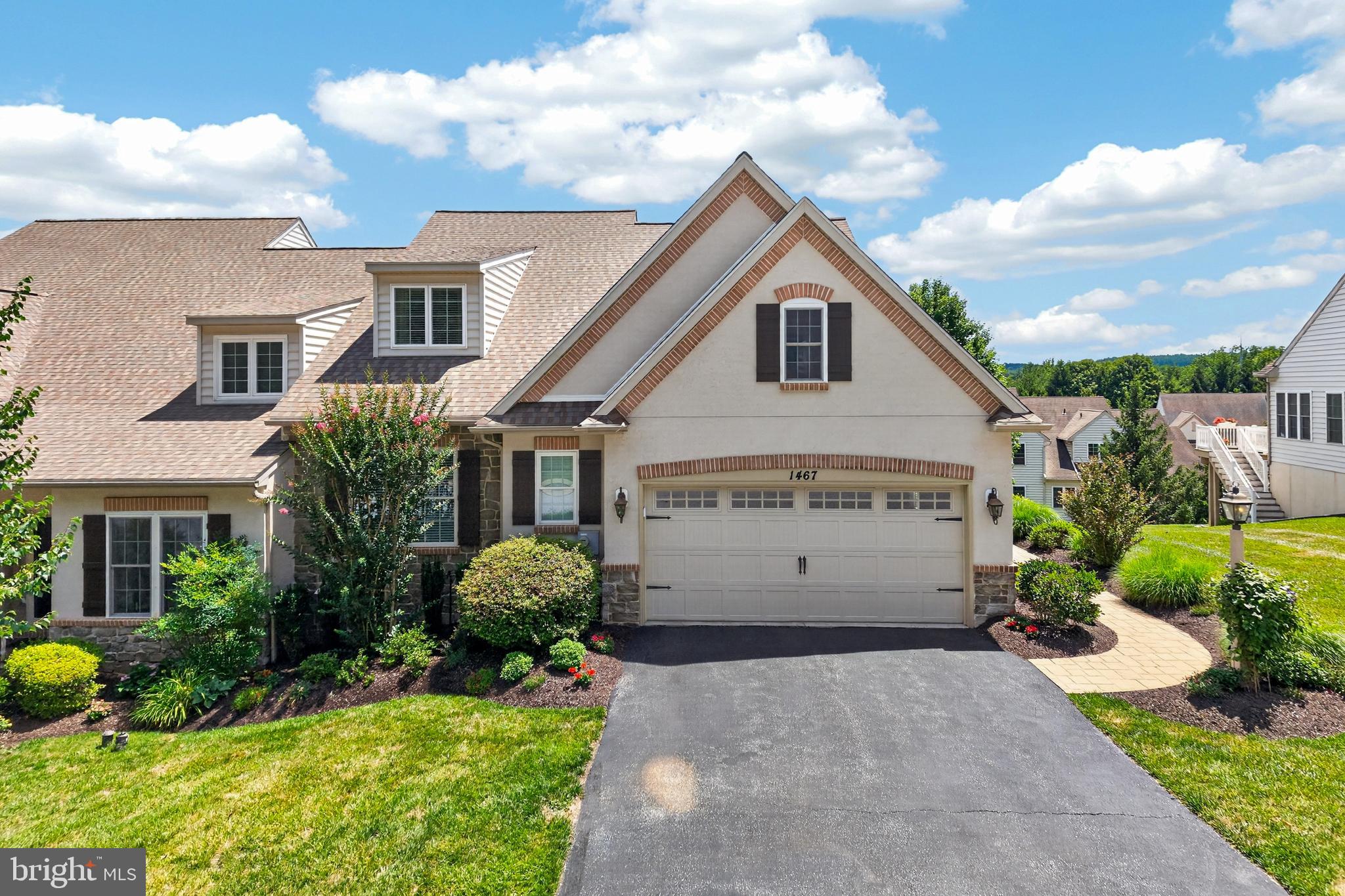 Welcome to this impeccably maintained end-unit carriage home in the sought-after 55+ community of Woods at Rock Raymond. Professionally designed landscaping and an irrigation system combine with extensive hardscaping to create exceptional curb appeal. A stamped concrete walkway leads to the front entrance, while an EP Henry staircase descends to the private rear patio, accented by low EP Henry stone walls. Enjoy outdoor living on the composite deck with a retractable awning or the patio below. Inside, a welcoming hardwood foyer opens to a dramatic great room with a vaulted ceiling, a stone gas fireplace, and abundant natural light. Adjacent to the great room, the sunroom features a ceiling fan and sliding doors leading to the deck. The kitchen offers granite countertops, a spacious island, stainless steel appliances, gas cooking, and a sunny breakfast room with hardwood flooring. A powder room and a laundry room complete with cabinetry and a folding counter add everyday convenience. The first-floor primary suite features a ceiling fan, crown molding, walk-in closet, and a private bath with a Corian shower, corner soaking tub, and custom built-in cabinet. Completing the main level is an attached two-car garage with painted walls, a coated floor, and storage cabinets. An oak staircase leads to the second level, where an open loft with custom built-ins overlooks the great room below, creating an attractive architectural focal point. Two additional bedrooms with ceiling fans and a Jack-and-Jill bath provide comfortable accommodations for family or guests. The finished walk-out lower level with 9-foot ceilings is an entertainer's dream, featuring a custom granite-topped bar with seating for eight, dishwasher, wine cooler, refrigerator, and built-in TV. A separate finished room offers flexibility for a fitness room, hobby room, or additional living space. Twin windows and a sliding glass door provide abundant natural light and direct access to the EP Henry patio. Additional highlights include a new roof, heating and air conditioning system (2018), neutral décor, wainscoting, central vacuum system, built-in speakers, and meticulous attention to detail throughout. Ideally located just minutes from shopping, restaurants, major commuter routes, and everyday conveniences, this move-in ready home offers low-maintenance living in one of the area's most desirable 55+ communities. Be sure to click on the virtual tour icon. Please note: The property's tax assessment is currently under appeal.