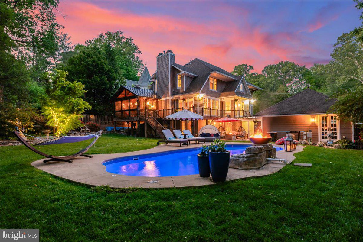 A rare offering in the coveted Cabin John neighborhood, this beautifully crafted arts-and-crafts home exudes warmth and character on the inside, paired with exceptional outdoor living spaces that feel like your own private resort retreat. Thoughtfully designed across four levels, the home features four spacious bedrooms and four baths, with easy potential for fifth and sixth bedrooms.
A welcoming foyer with a graceful curved staircase sets the tone from the moment you enter. Rich architectural details throughout the home include nine-foot ceilings, arched doorways, a mahogany built-in bookcase, a spectacular screened-in porch, and three fireplaces.
The main level features a spacious great room, an open kitchen with marble countertops, custom cabinetry, and a coffee bar with instant hot water, as well as a separate breakfast room, a walk in pantry and an additional living area that can function as either a formal dining room or formal living room. A private office — easily converted into a bedroom — and a full bath are also located on the main level, offering flexibility for guests or multigenerational living. The kitchen connects seamlessly to the screened-in porch and wraparound deck, creating an easy flow between indoor and outdoor living spaces.
The screened porch is spectacular, affectionately known as the “Zen Room,” features dramatic double-height antique barn post-and-beam construction with a firepit at its center, evoking the warmth and charm of a cozy mountain lodge.
Upstairs features three generously sized bedrooms and two baths, including a spacious primary suite with cathedral ceilings, fireplace, walk-in closet, and additional closet space. The second level also includes a sitting nook and laundry room. The fully finished attic level provides a bonus space and could easily function as a fifth bedroom, office, studio, or a fun playroom.
The outdoor living spaces are truly exceptional and serve as the centerpiece of the property — a private retreat rarely found this close-in. At the heart of the backyard is a stunning saltwater pool with waterfall and firebowl feature, surrounded by expansive patios, decking, and multiple areas for entertaining and relaxation as well as several storage spaces.
The fully finished walkout lower level was completely renovated in 2019 and features wood-look ceramic tile flooring, a custom dry bar, and a large finished storage room that could easily be converted into a sixth bedroom. Approximately 70% above grade with large windows, the space offers exceptional versatility for guests, recreation, fitness, or additional living space.
Moments from Washington, downtown Bethesda, and Northern Virginia, with the C & O Canal just steps away, this exceptional home is also located within the highly regarded Whitman school cluster.