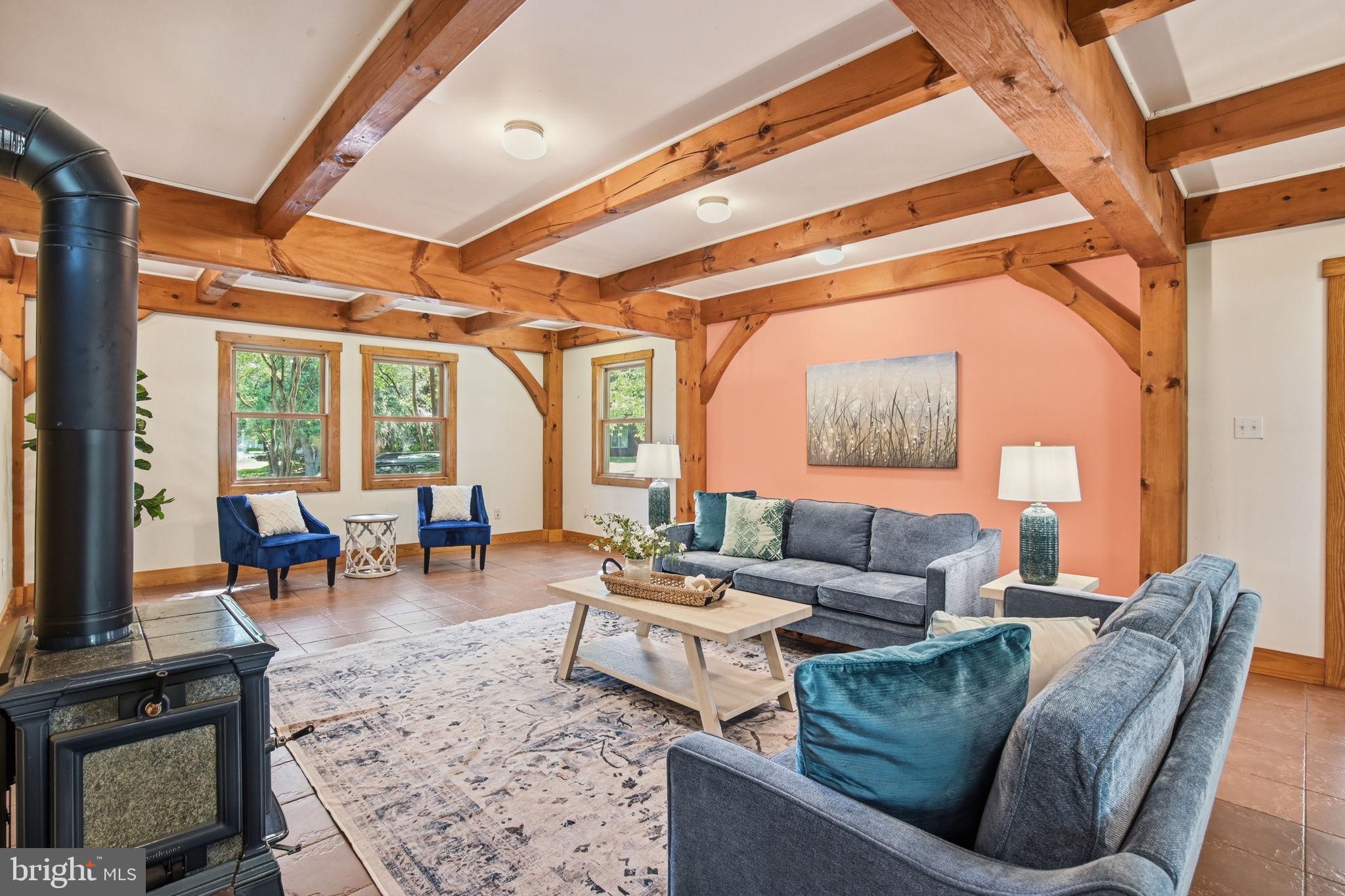 Blending warmth, character, and thoughtful updates, this beautifully maintained post-and-beam home offers a truly inviting living experience both inside and out. The spacious main level features all tile flooring, a huge living room anchored by a cozy wood stove, a flexible study/sitting room, and a charming 3-season room. The kitchen and dining combination creates an ideal gathering space with granite countertops, freshly painted cabinetry, and easy access to the mudroom/laundry area. Radiant heat serves as the primary heat source, adding efficient comfort throughout the home, while a convenient half bath completes the first floor. Upstairs, hardwood floors run throughout all three bedrooms, including a spacious primary suite with heated bathroom floors, soaking tub, and separate shower. The hall bath has been tastefully updated with a tile shower and upgraded vanity. Additional improvements include added insulation along the sides of the home, new drywall throughout, a metal roof, and a dry basement with French drain system, dehumidifier, and storage space. Outdoor living shines with a large wood porch overlooking the fenced backyard with mature native gardens.. A detached oversized two-car garage and additional rear parking via alley access provide plenty of space for vehicles, hobbies, or storage. This home combines timeless charm, functional updates, and exceptional comfort in a setting designed to enjoy year-round.