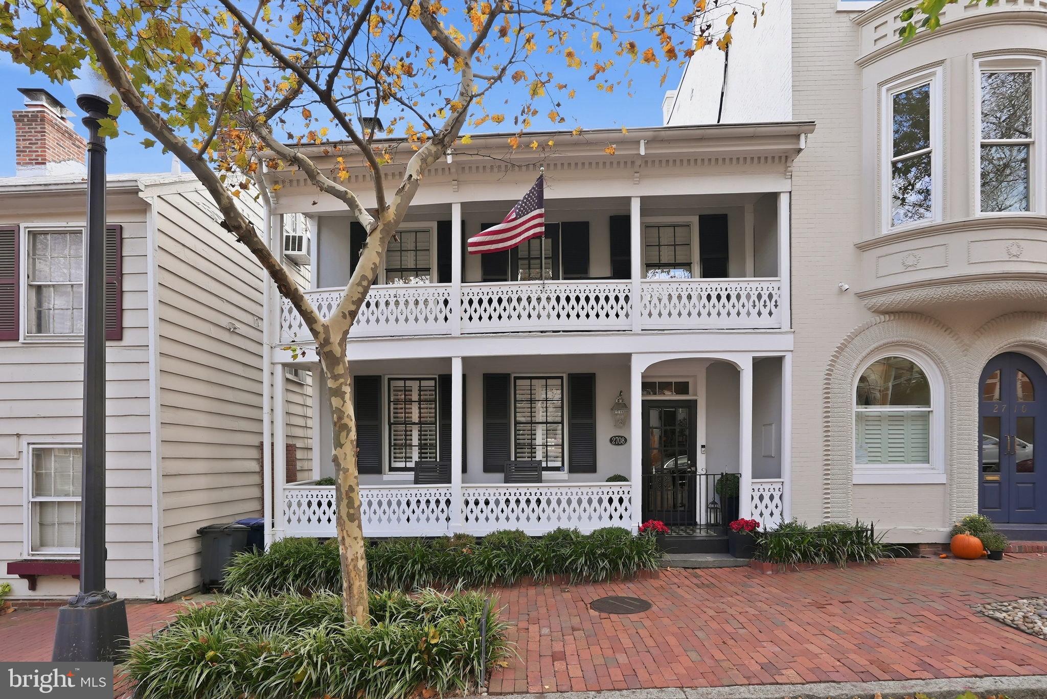 BEAUTIFULLY UPDATED HOME IN GEORGETOWN’S EAST VILLAGE  WITH 2-CAR PARKING! Steeped in history and beautifully renovated for modern living, 2708 P Street NW is a rare Georgetown jewel dating back to the 1790s. Distinguished curb appeal begins with its iconic Louisiana-style two-story front porches, freshly restored floorboards, custom ironwork, and newly installed architectural lighting that highlights the home’s historic façade at night. Boasting 3 Bedrooms, 3.5 Bathrooms, and over 3,100 sqft across 3 stories of beautifully renovated living spaces, this gorgeous home features triple exposures and large windows that fill the home with an abundance of natural light at every turn, while six fireplaces (four converted to remote-controlled gas) anchor the home with timeless charm. A comprehensive 2019 renovation introduced top-tier Kitchen appliances, custom stone accent walls, bespoke millwork, designer lighting, modern stair railings, curated window treatments, and more. The Kitchen and main living spaces are framed by three stories of insulated, floor-to-ceiling glass doors, flooding the interiors with natural light and creating a seamless indoor-outdoor flow ideal for entertaining. Upstairs, the Primary Suite is a true retreat, featuring oversized windows, a fireplace, custom closets, and a fully renovated spa bath complete with heated floors, upgraded fixtures, and its own fireplace. Additional rooms include the second Bedroom which offers access to the second story front porch plus a flexible bonus room perfect for a home office or sitting room. The Lower Level offers exceptional versatility with a third Bedroom and Bath, an expansive Family Room with walkout access, and a secondary Kitchen/storage area appointed with new flooring, custom cabinetry, and granite counters. The private rear Patio has been completely redesigned with new landscaping and hardscaping, and features a built-in gas grill, custom fountain, and integrated outdoor speakers—an inviting extension of the home’s living space. Two-car parking, accessed from Poplar Street, is an extraordinary Georgetown luxury. Additional upgrades include an eco-friendly A/C system, updated water lines, new gutter system, smart washer/dryer, new boiler valve system, exterior downlighting, new fencing and gates, and a state-of-the-art security camera and lighting system. Meticulously restored and thoughtfully enhanced, this exceptional residence offers timeless Georgetown character with every modern comfort just moments from the neighborhood’s finest dining, shopping, and waterfront.
